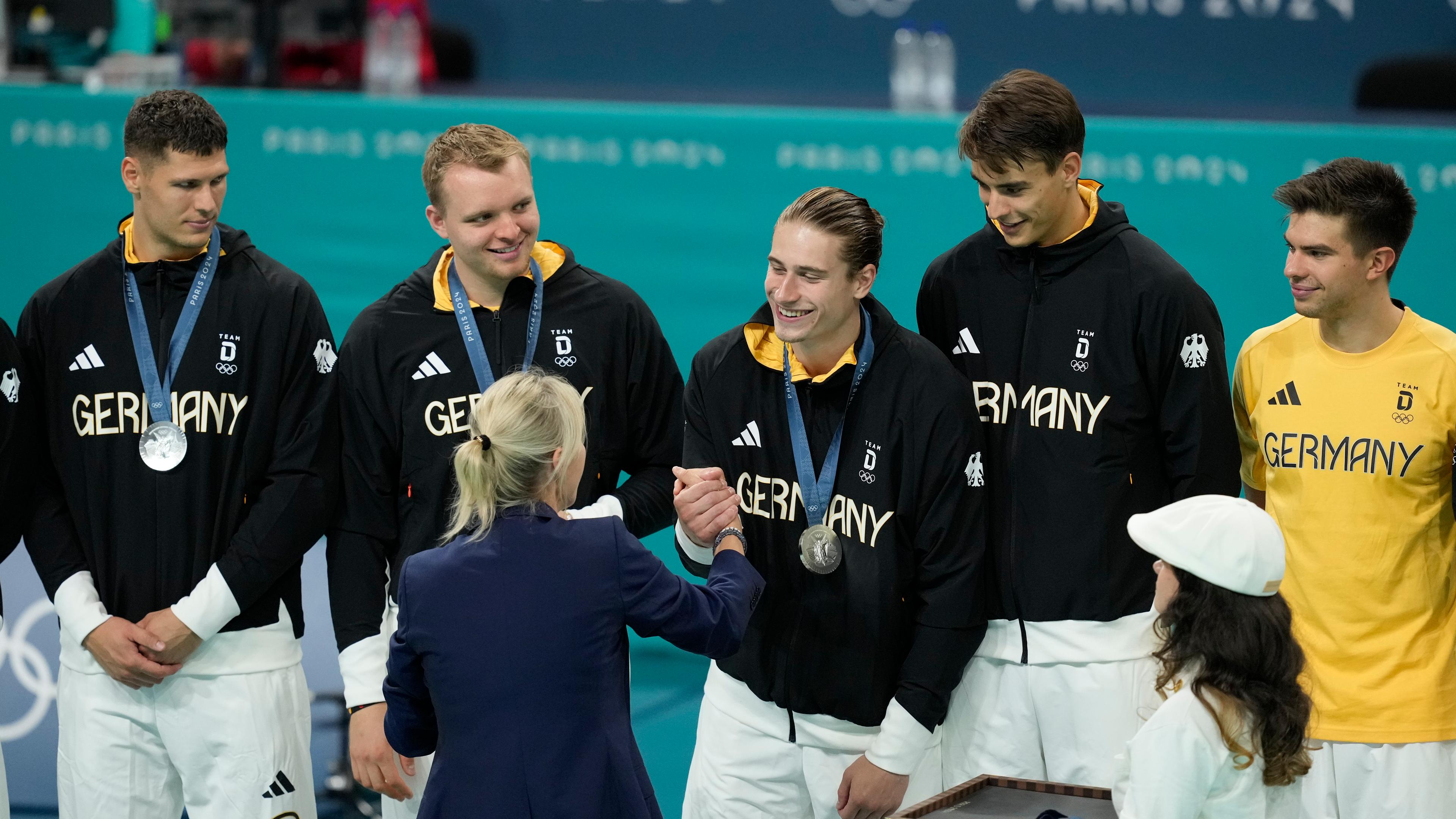 IOC-Mitglied Britta Heidemann überreicht an die deutschen Handballer die olympische Silbermedaille am 11.8.2024.