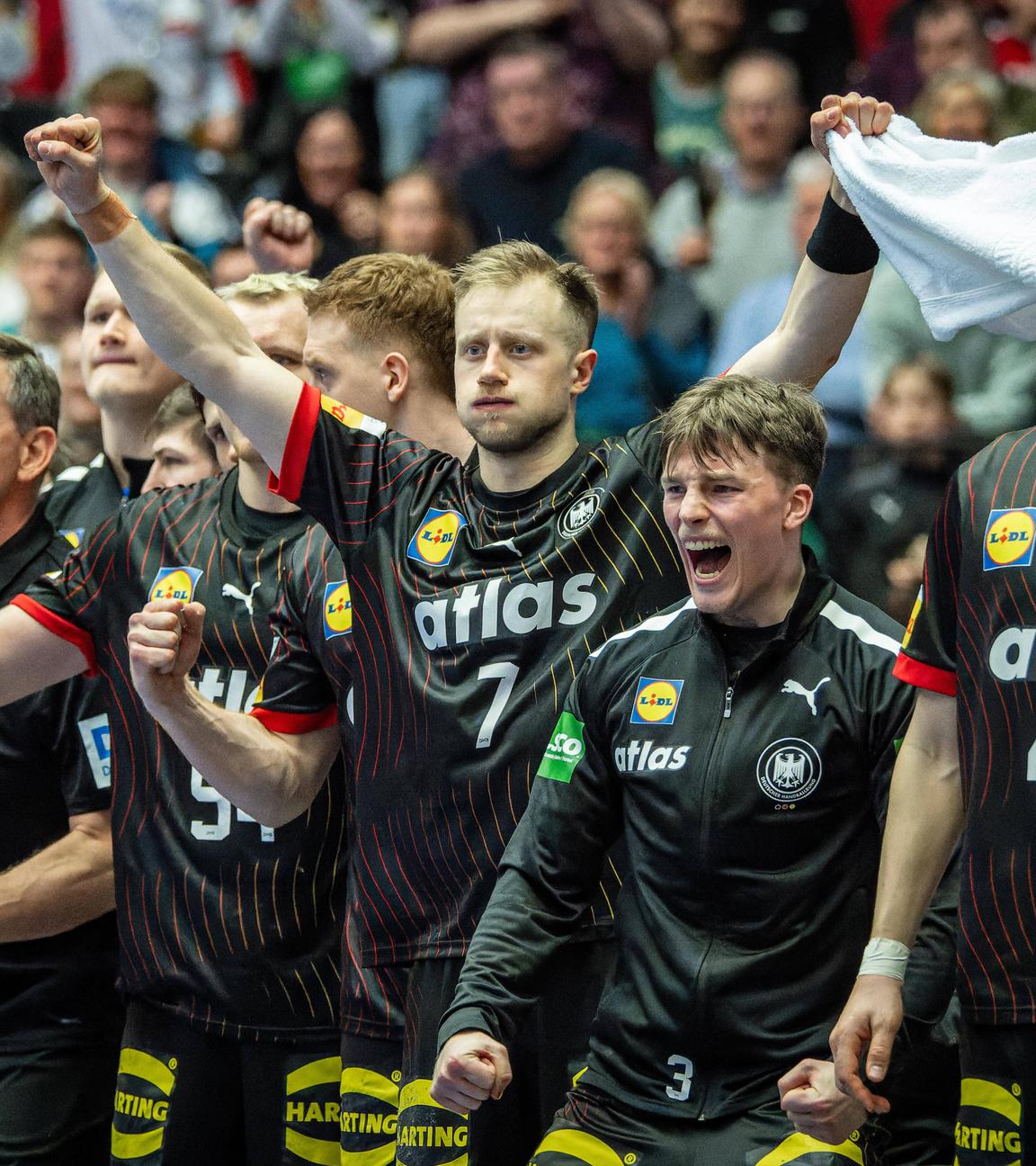 Die deustche Handballnationalmannschaft jubelt am Seiternrand.