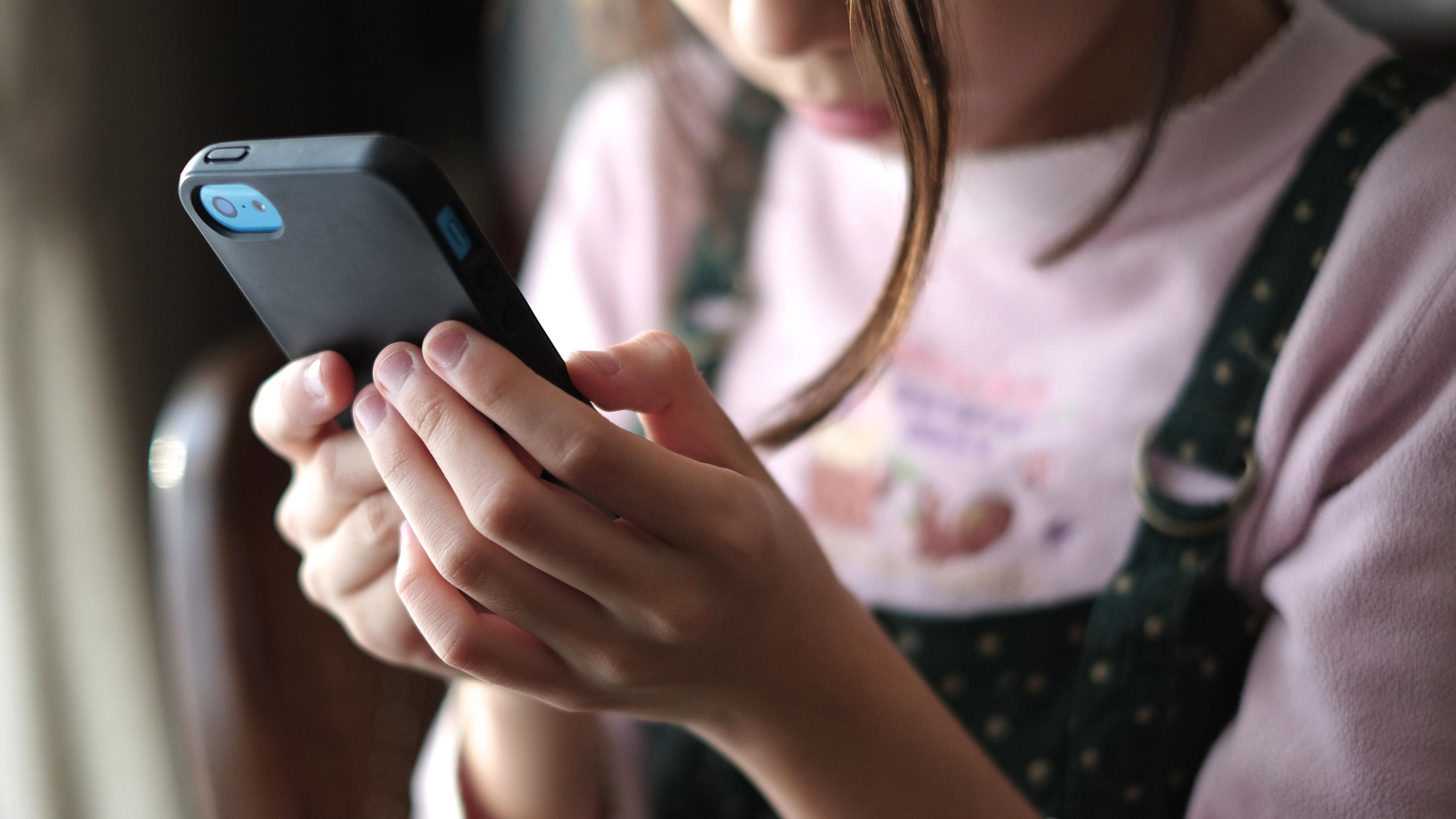 Ein junges Mädchen schaut auf den Bildschirm ihres Smartphones.