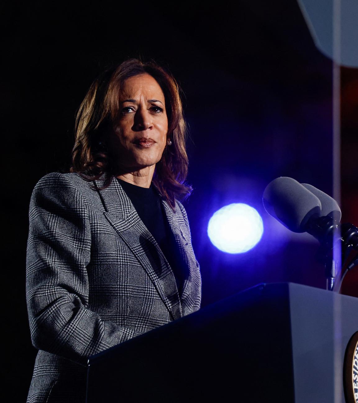 Kamala Harris steht hinter einem Pult und schaut nach links in Richtung der Kamera. 