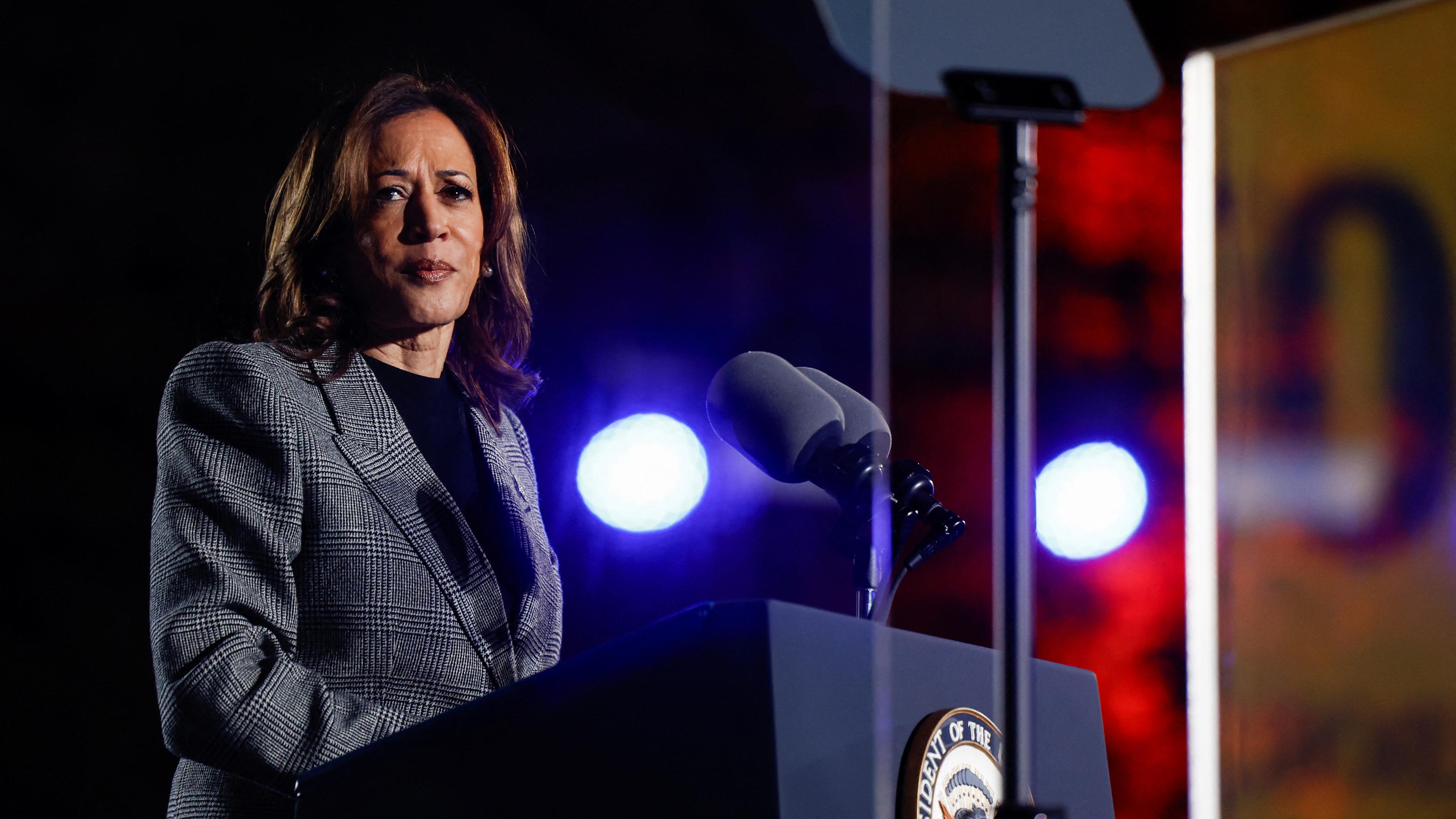 Kamala Harris steht hinter einem Pult und schaut nach links in Richtung der Kamera. 