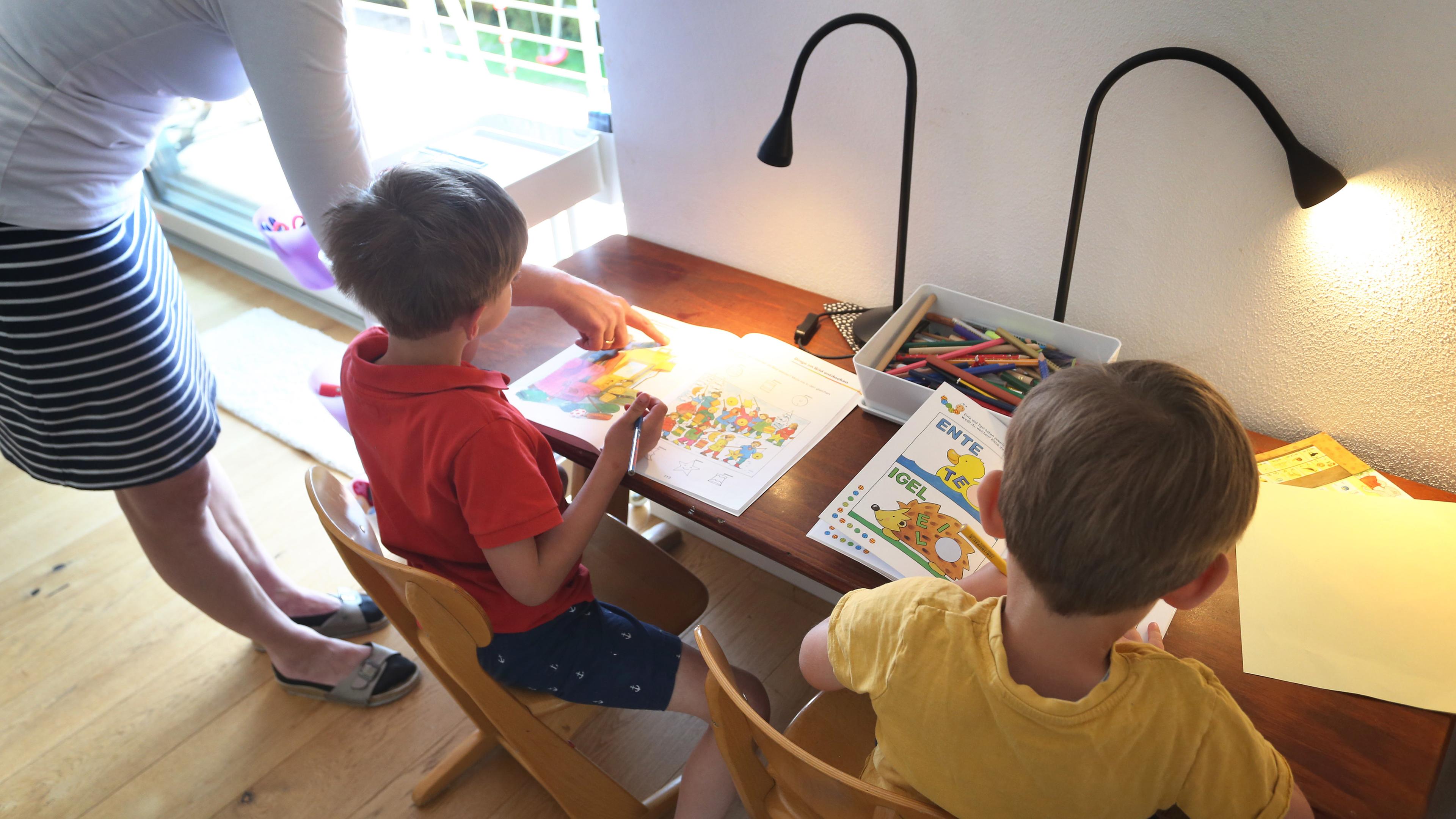 Eine Mutter hilft ihren Kindern bei den Hausaufgaben.