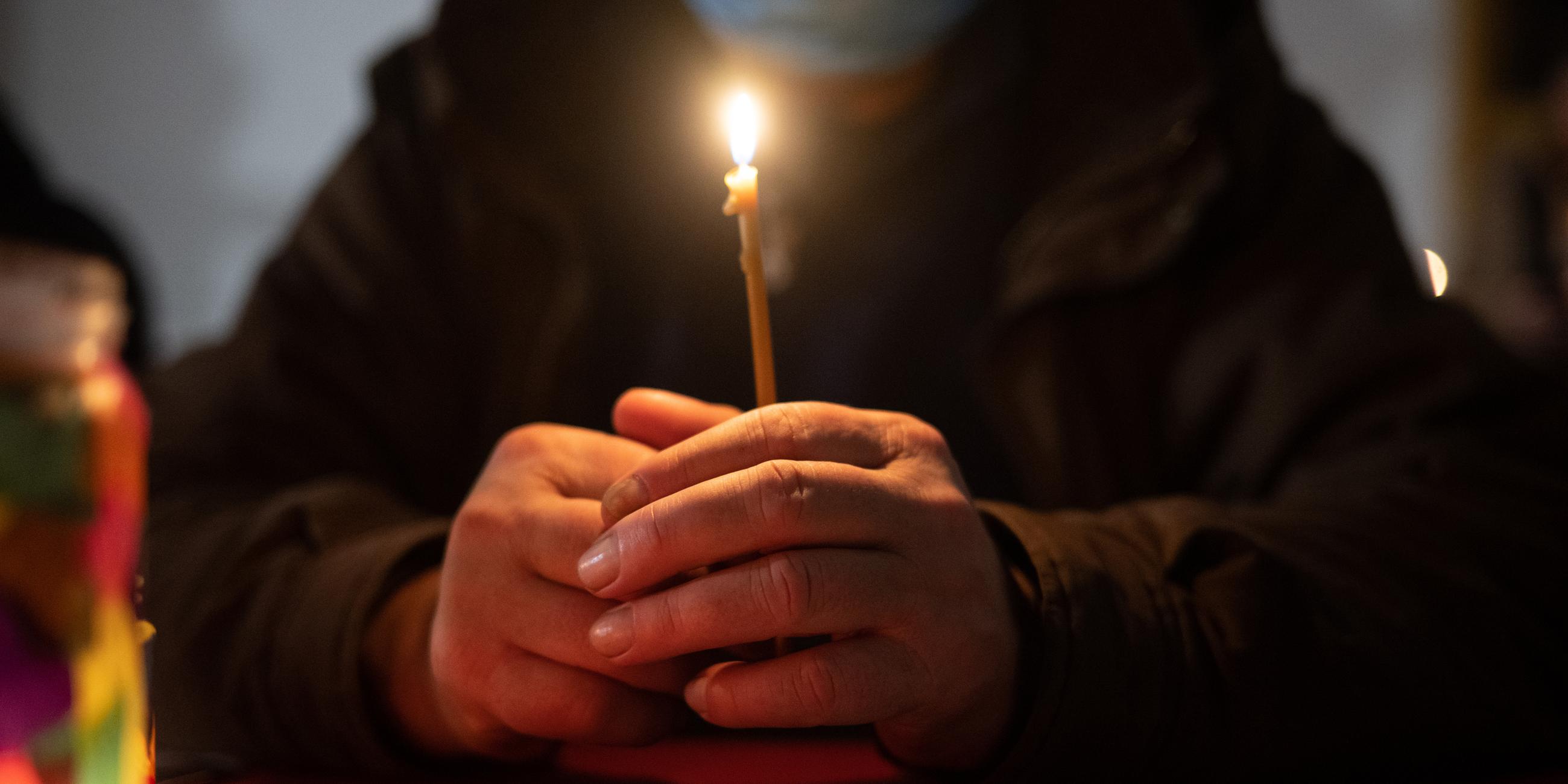 Hessen, Frankfurt/Main: Ein Besucher sitzt während der ·Langen Nacht am Heiligen Abend· in der Weißfrauen Diakoniekirche Frankfurt mit einer Kerze beim Gottesdienst an einem Tisch. Archivbild