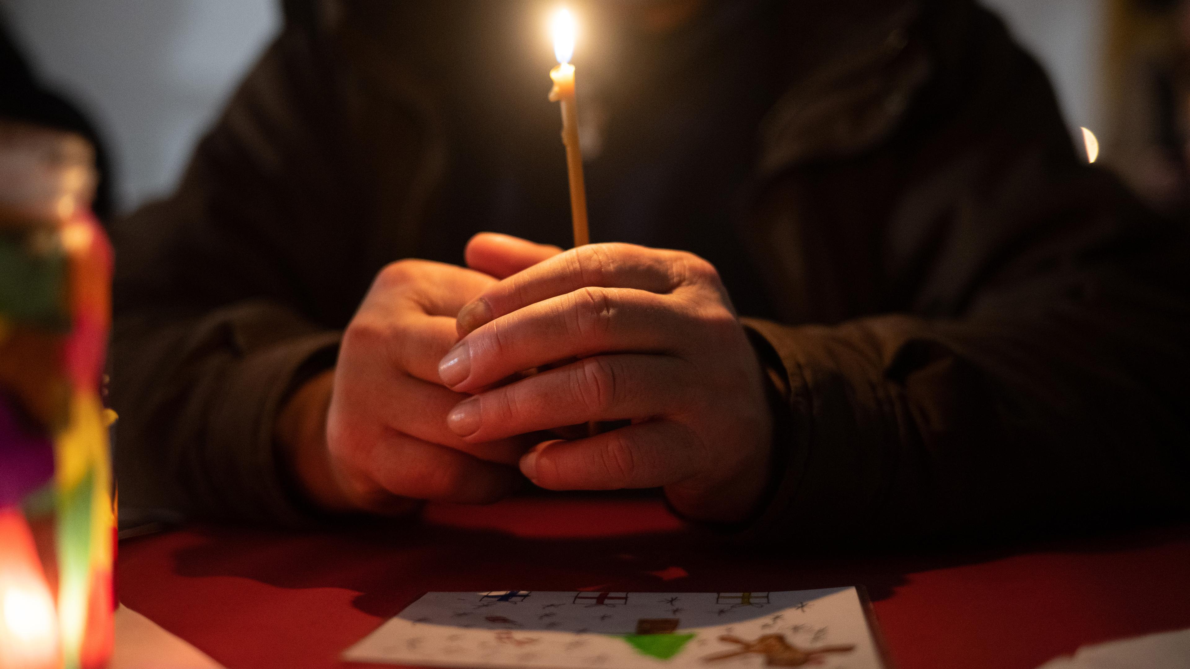 Hessen, Frankfurt/Main: Ein Besucher sitzt während der ·Langen Nacht am Heiligen Abend· in der Weißfrauen Diakoniekirche Frankfurt mit einer Kerze beim Gottesdienst an einem Tisch. Archivbild