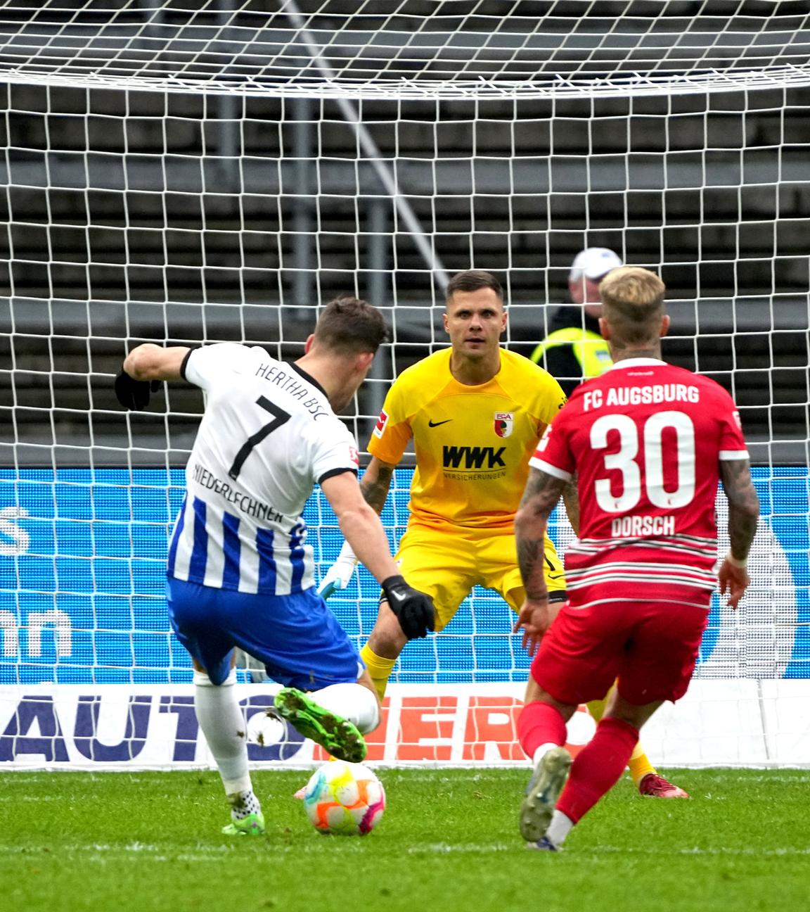 25.02.2023, Berlin: Fußball: Bundesliga, Hertha BSC - FC Augsburg, 22. Spieltag, Olympiastadion, Herthas Florian Niederlechner (l) schiesst aufs Tor von Augsburgs Torhüter Rafal Gikiewicz.