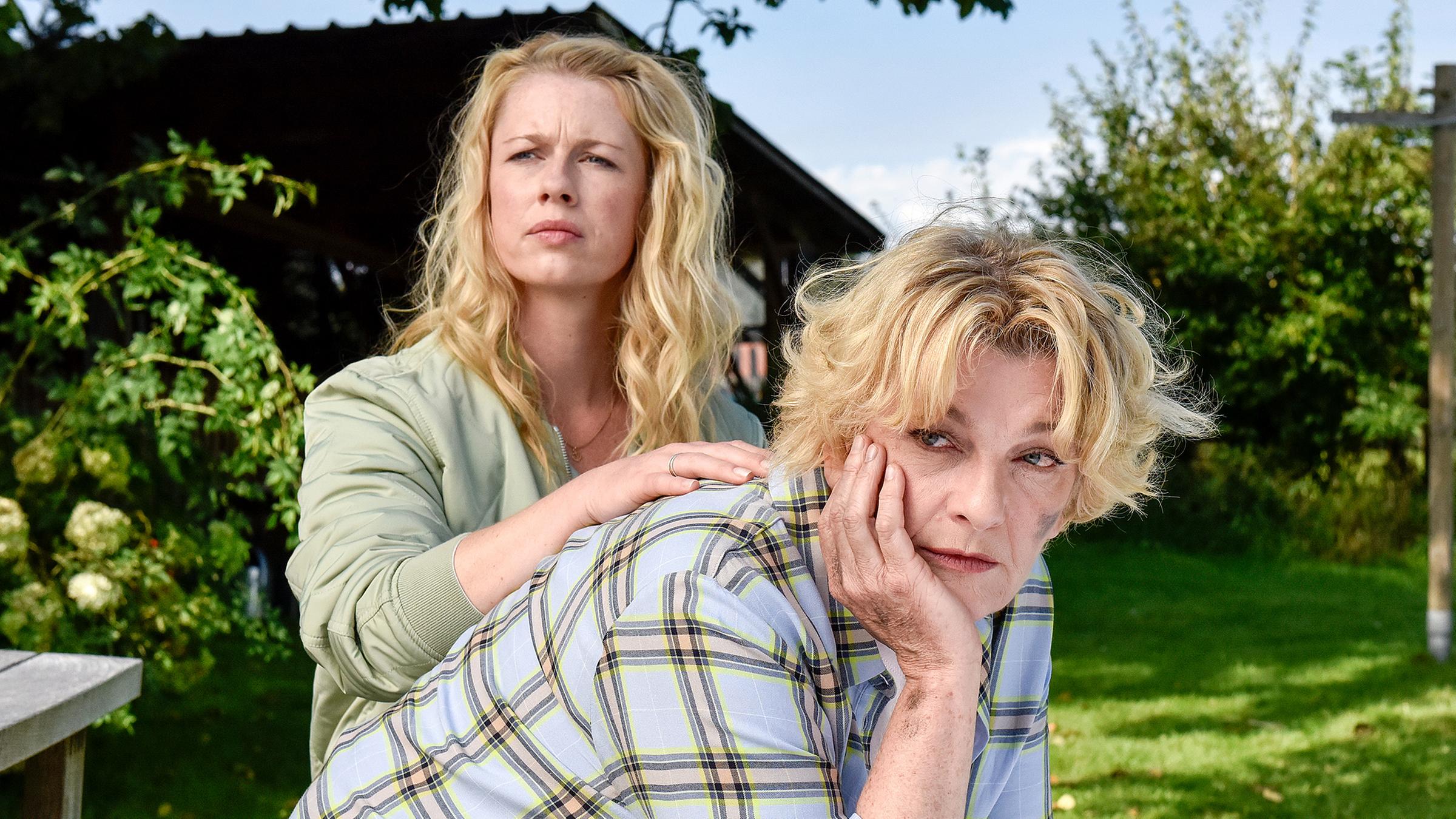 Marie Reiter (Christine Eixenberger) sitzt mit ihrer Mutter Irene (Saskia Vester) im Garten und legt dieser ihre Hand auf die Schulter.