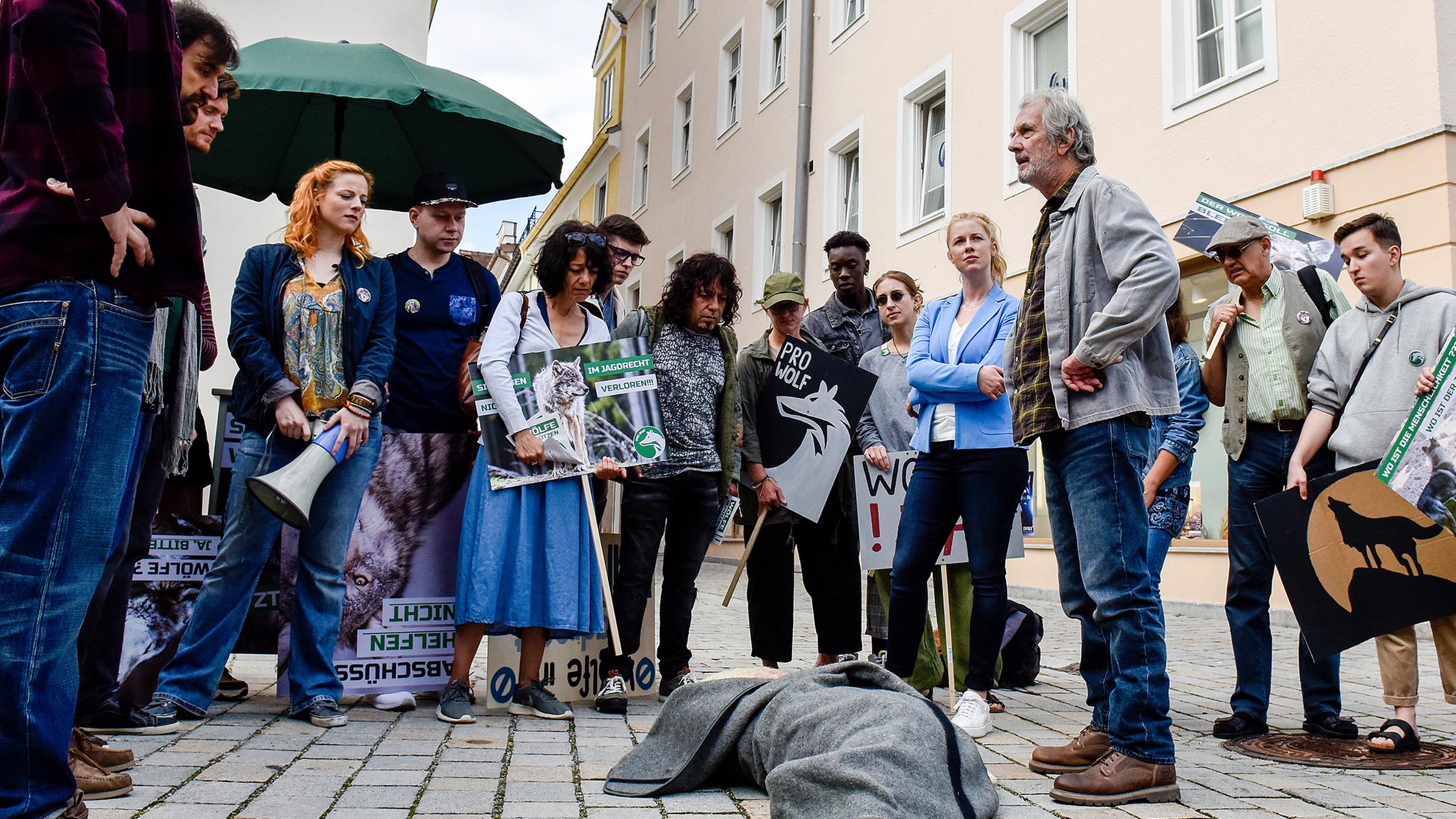 Anton Ziegler (Peter Prager, r.) zeigt den Demonstranten um Martin Theiner (Sebastian Fräsdorf, l.) das von einem Wolf gerissene Schaf. Marie Reiter (Christine Eixenberger) steht links neben Anton, um eine Eskalation der Situation zu verhindern.