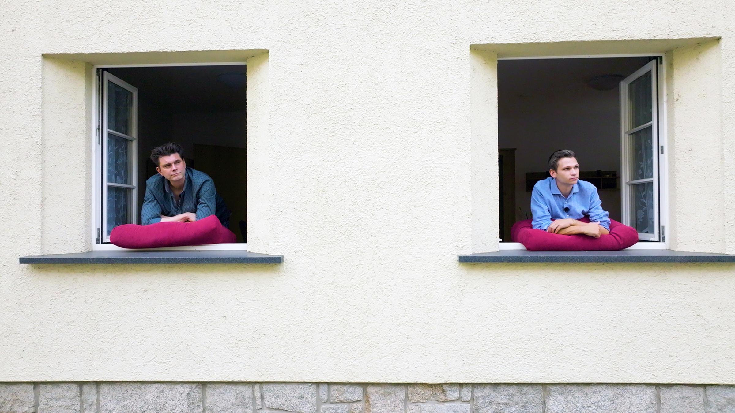 Lutz van der Horst und Fabian Köster schauen aus den Fenstern ihrer "Probewohnung" in Görlitz.