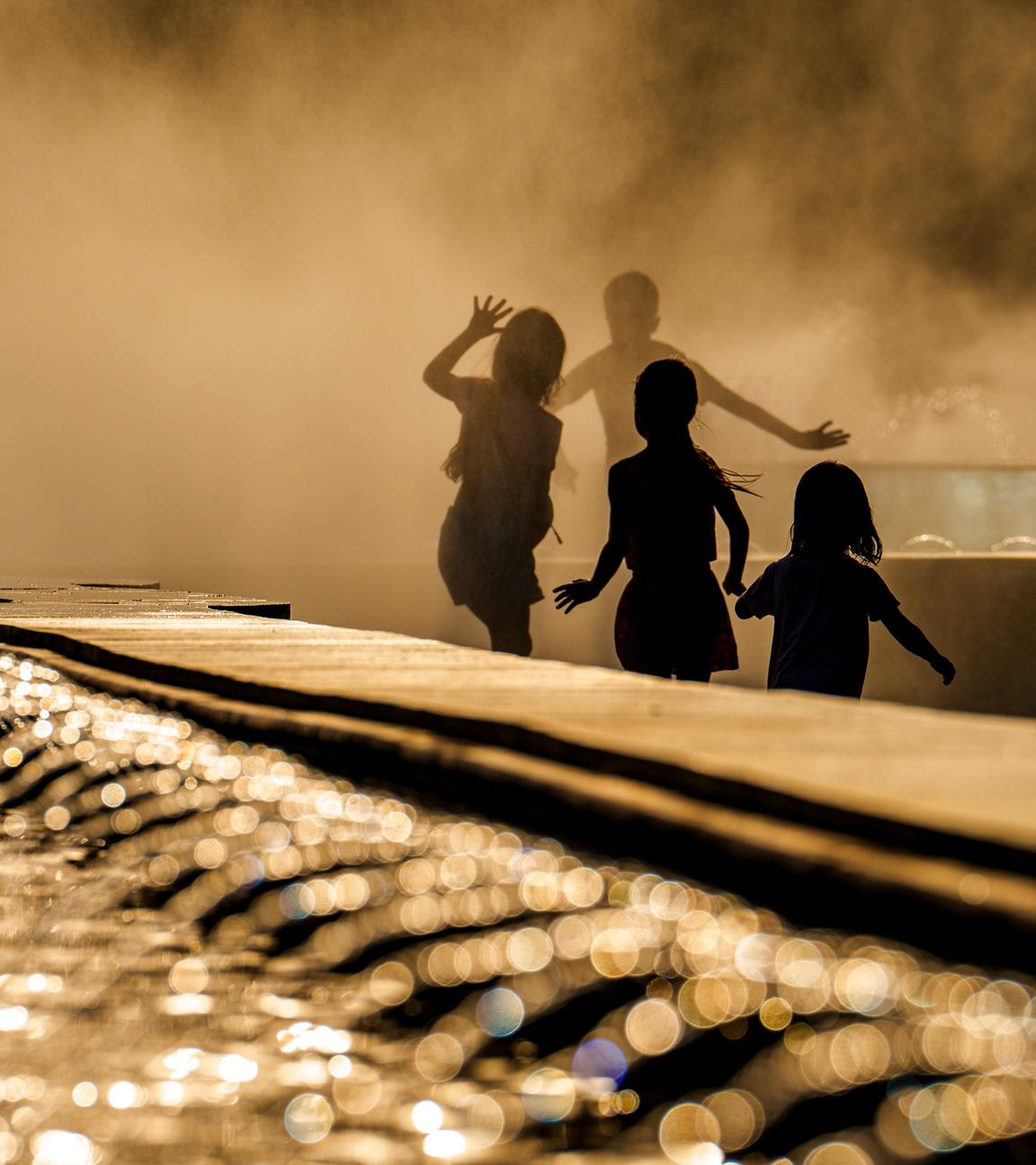 Rumänien, Bukarest: Kinder genießen das Wasser aus einem öffentlichen Brunnen vor Sonnenuntergang, als die Temperaturen 38 Grad Celsius überschritten hatten.