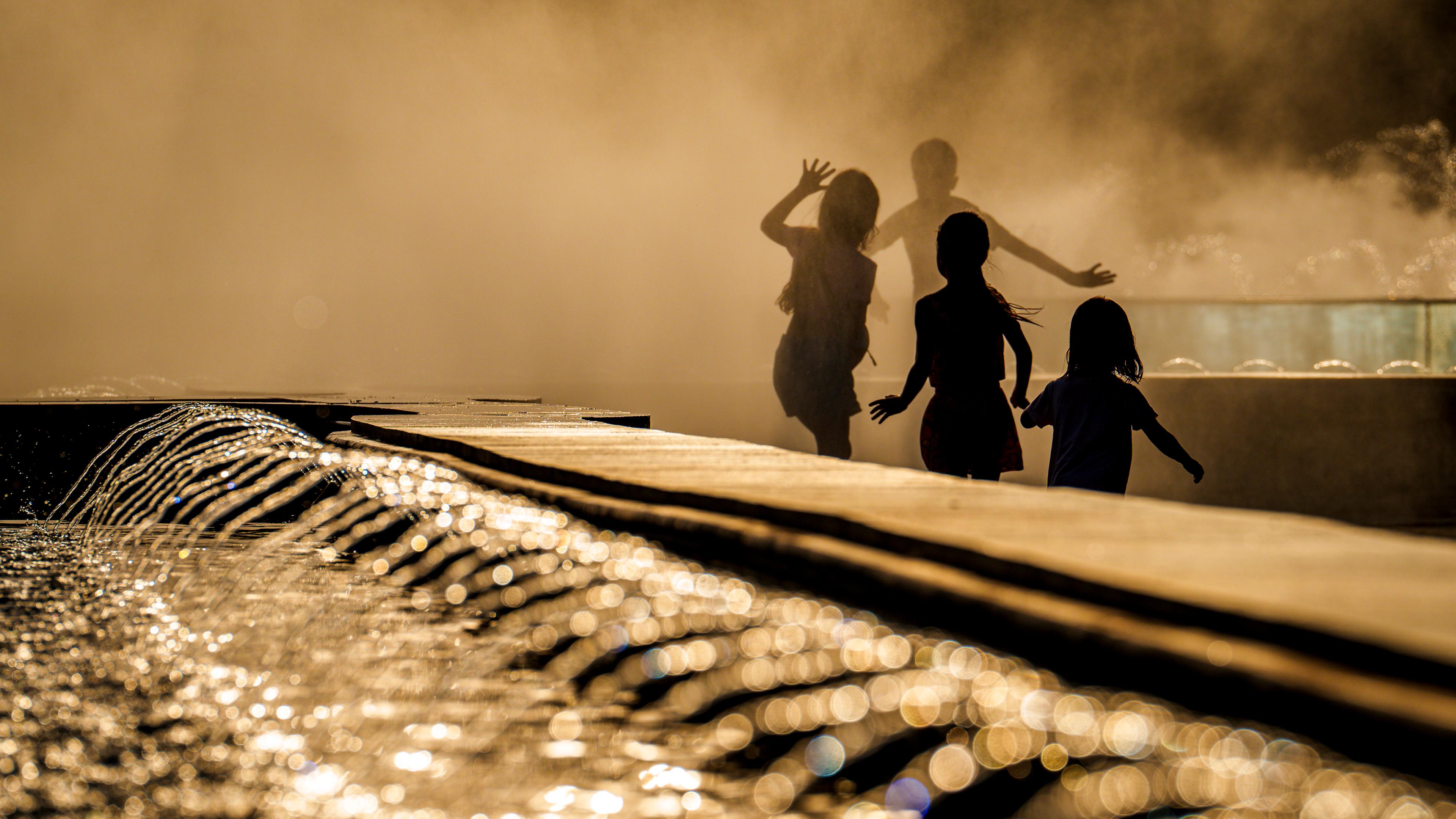 Rumänien, Bukarest: Kinder genießen das Wasser aus einem öffentlichen Brunnen vor Sonnenuntergang, als die Temperaturen 38 Grad Celsius überschritten hatten.
