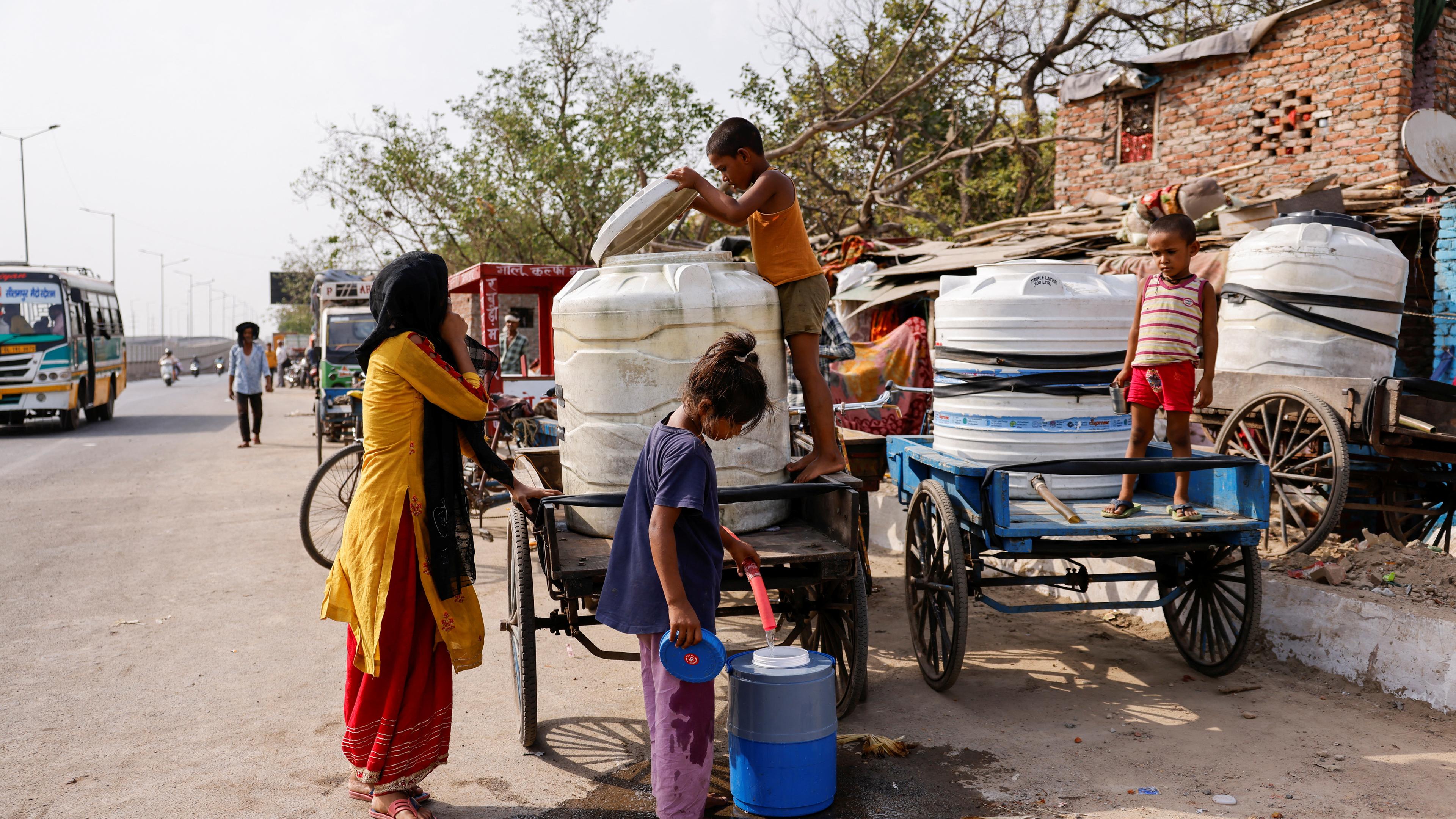 Ein Mädchen füllt Wasser in einer Wasserkühler an einem heißen Tag während der noch immer anhaltenden Hitzewelle in Neu-Delhi, Indien. 