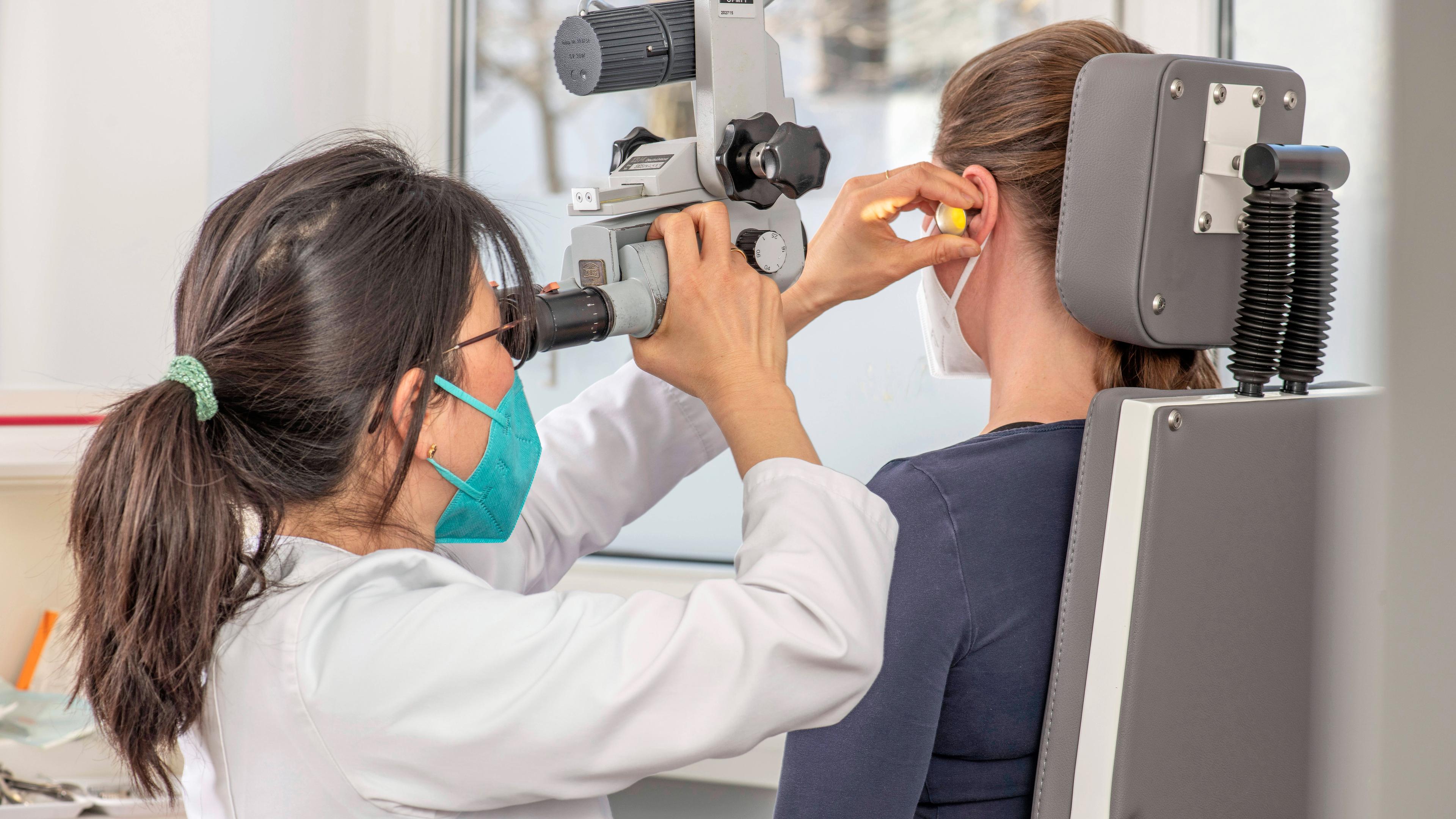 HNO-Fachärztin untersucht mit einem Mikroskop das Ohr einer Patientin, aufgenommen am 08.04.2022 in München, 