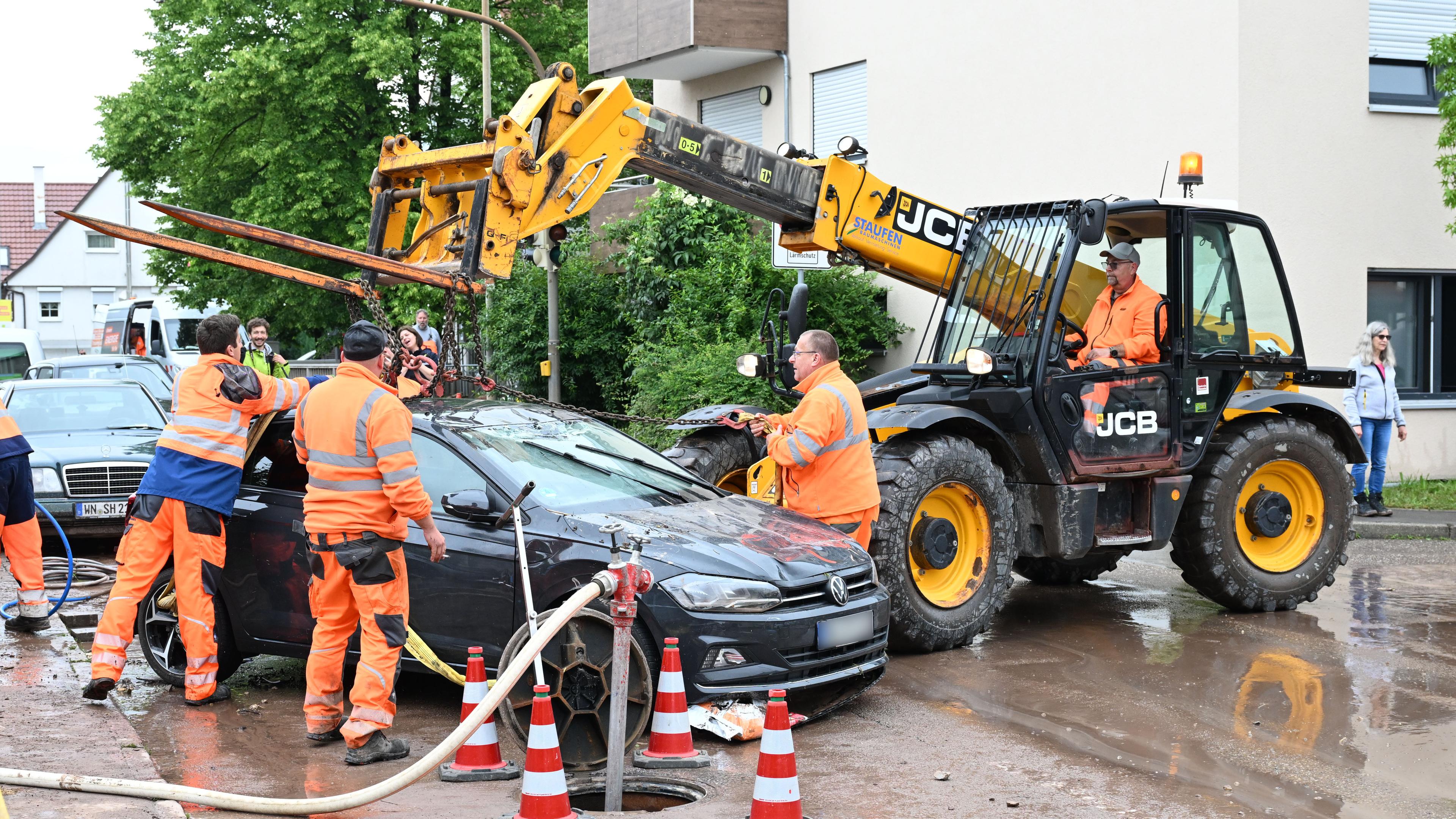 Baden-Württemberg, Miedelsbach: Helfer bergen ein Fahrzeug, das durch ein Unwetter zerstört wurde. 