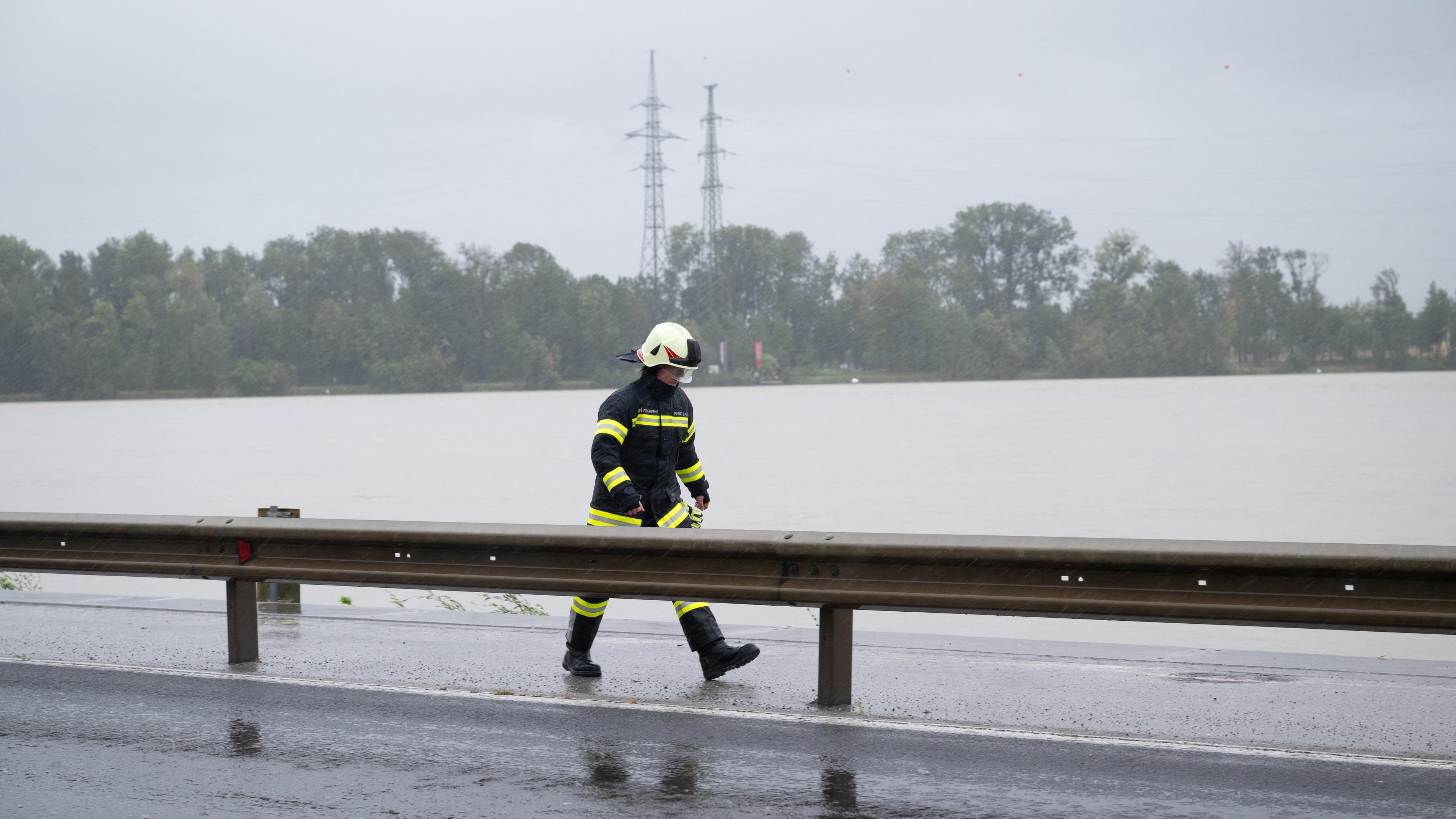 Feuerwehrmann vor überfluteter Straße