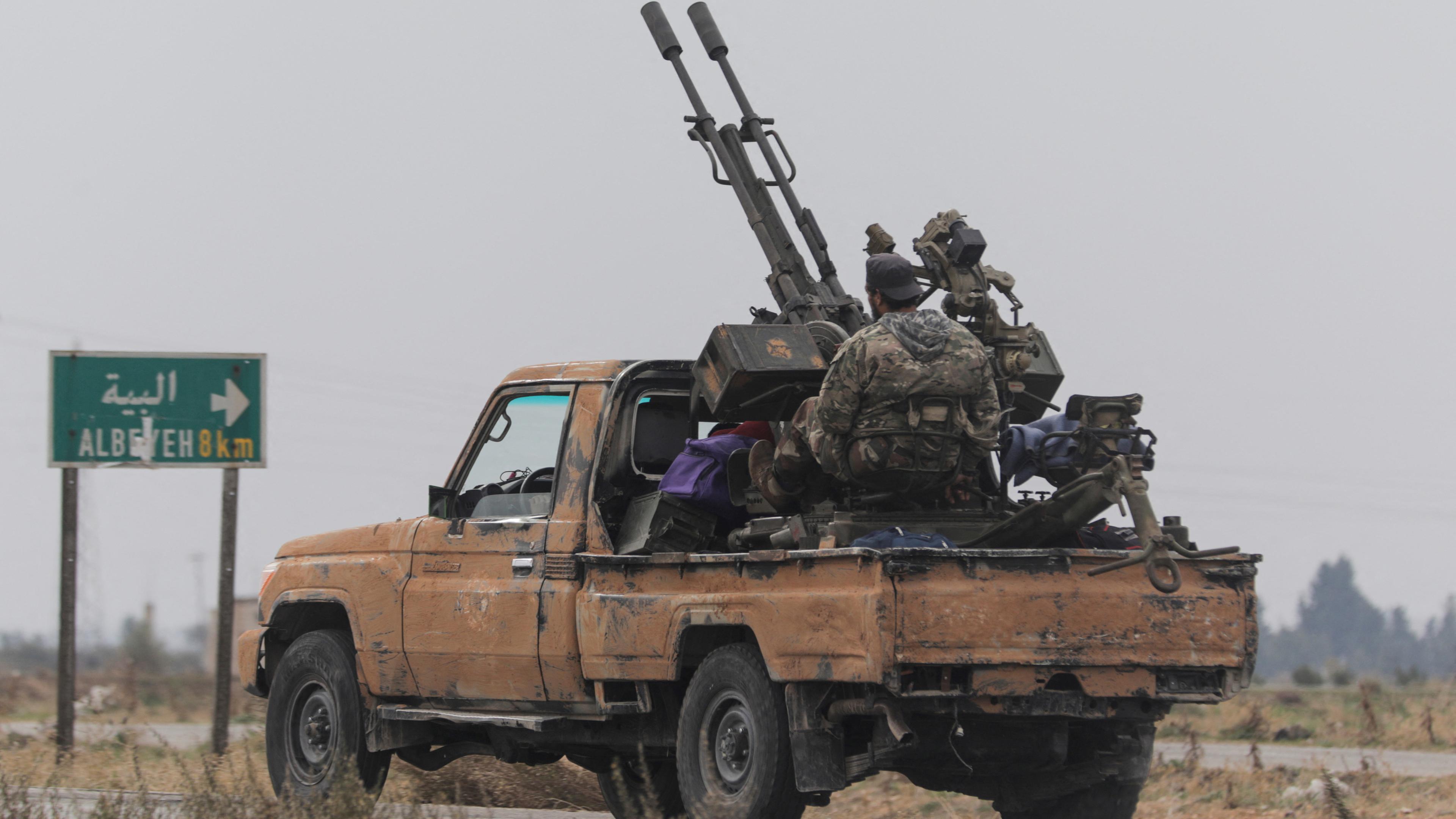 A rebel fighter sits on the back of a vehicle in Homs countryside