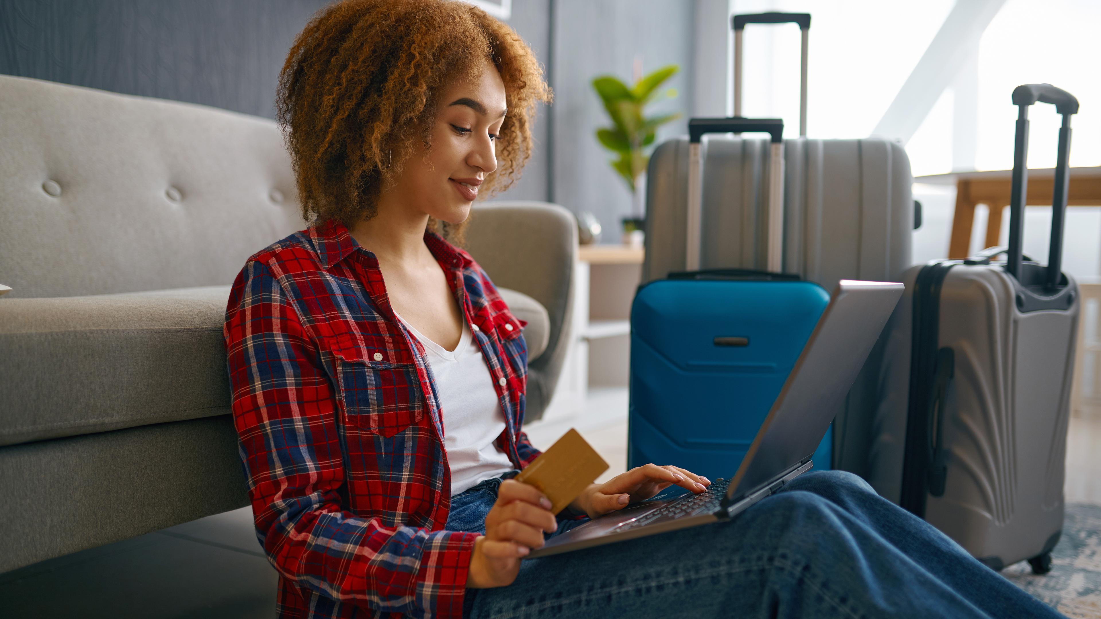 Eine junge Frau bucht eine Reise online am Laptop