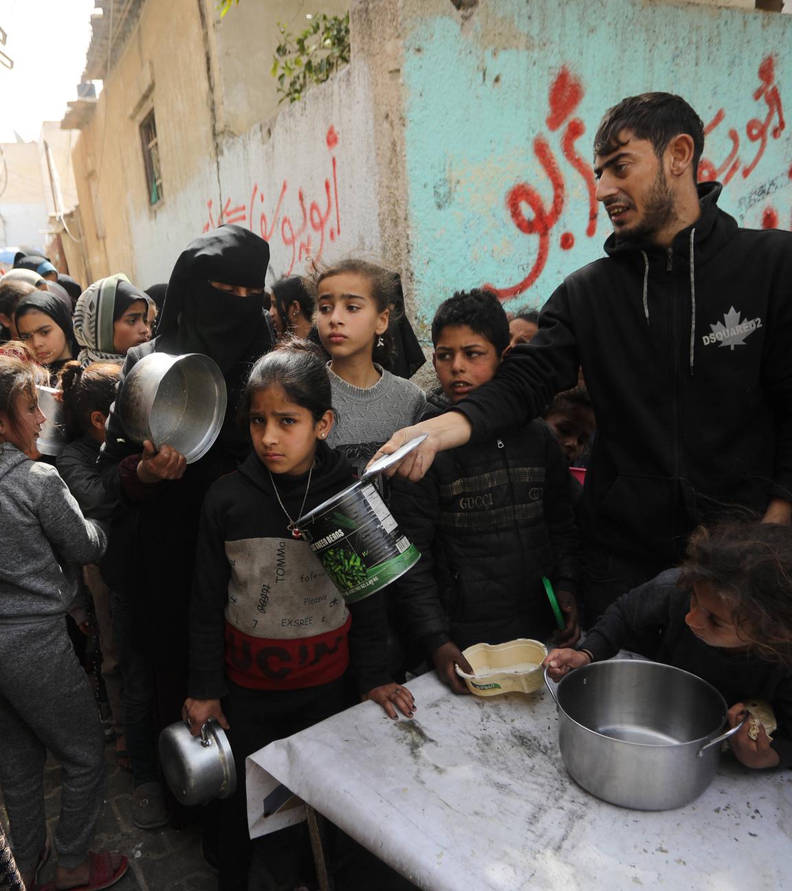 Palästinenser warten am Samstag, dem 2. März 2024, in einer provisorischen Wohltätigkeitsküche in Rafah im südlichen Gazastreifen auf eine Portion Essen.