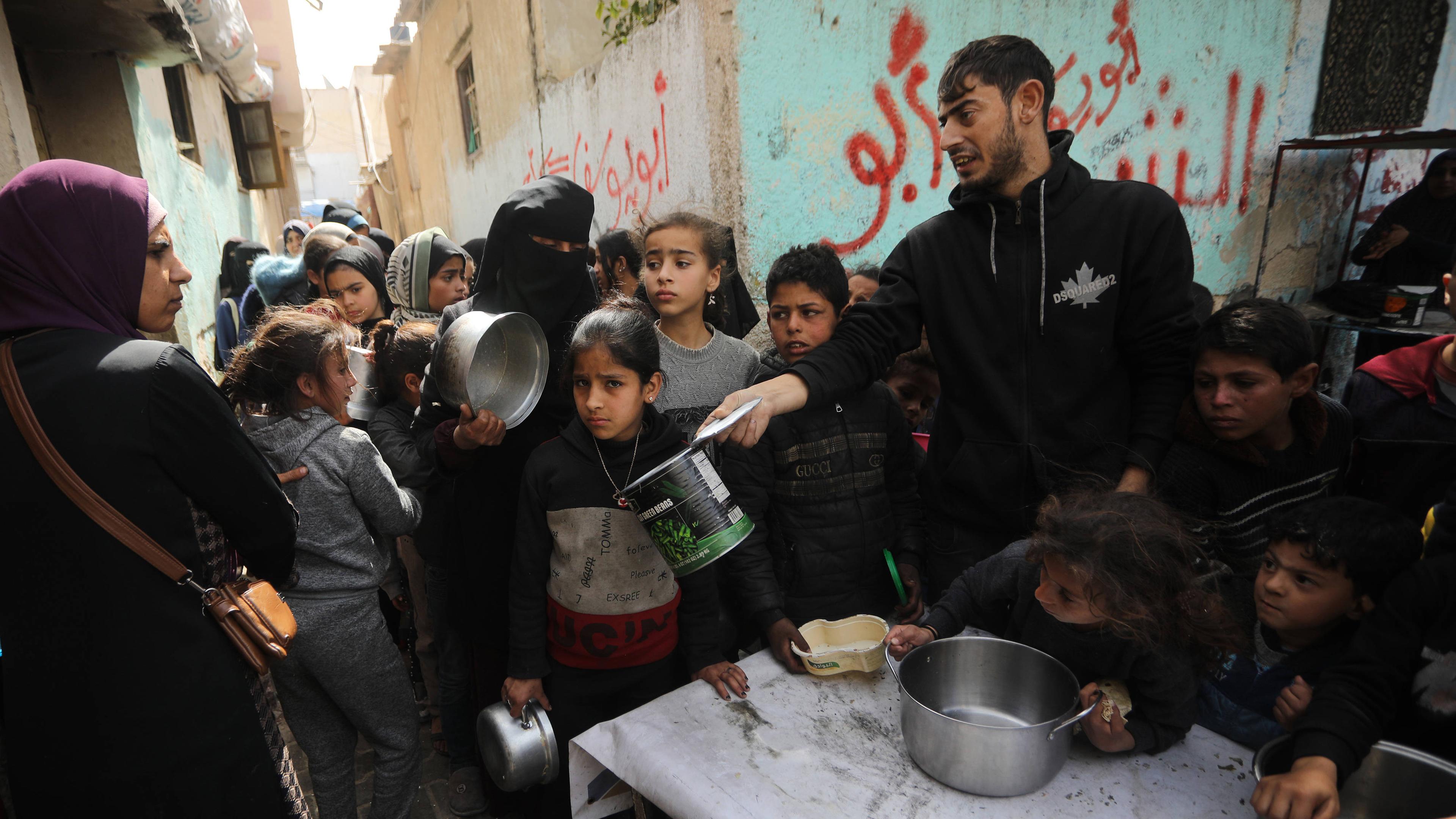 Palästinenser warten am Samstag, dem 2. März 2024, in einer provisorischen Wohltätigkeitsküche in Rafah im südlichen Gazastreifen auf eine Portion Essen.