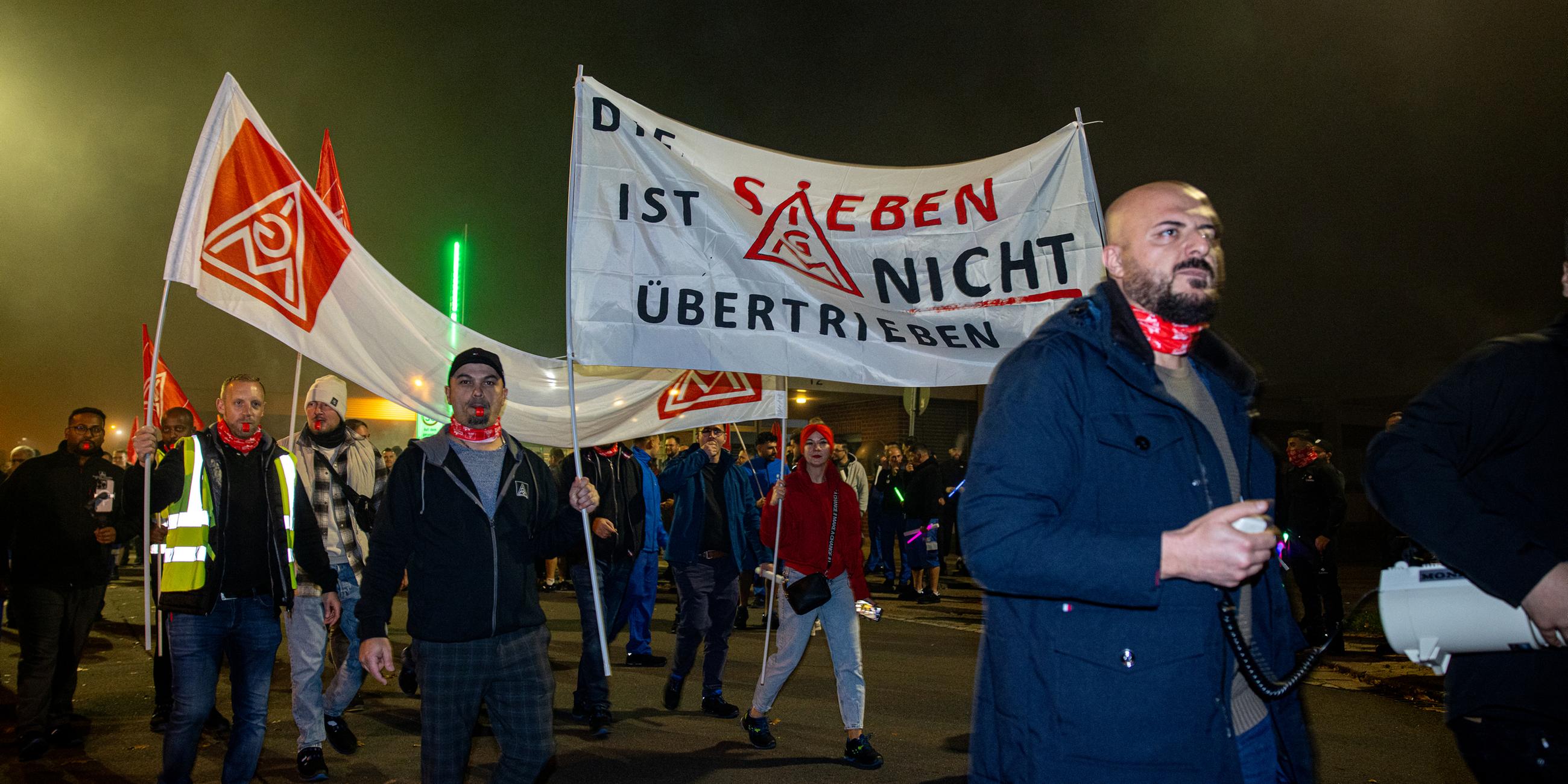 Mitarbeiter der ZF Friedrichshafen AG demonstrieren mit Fahnen und Fackeln vor dem Werk.