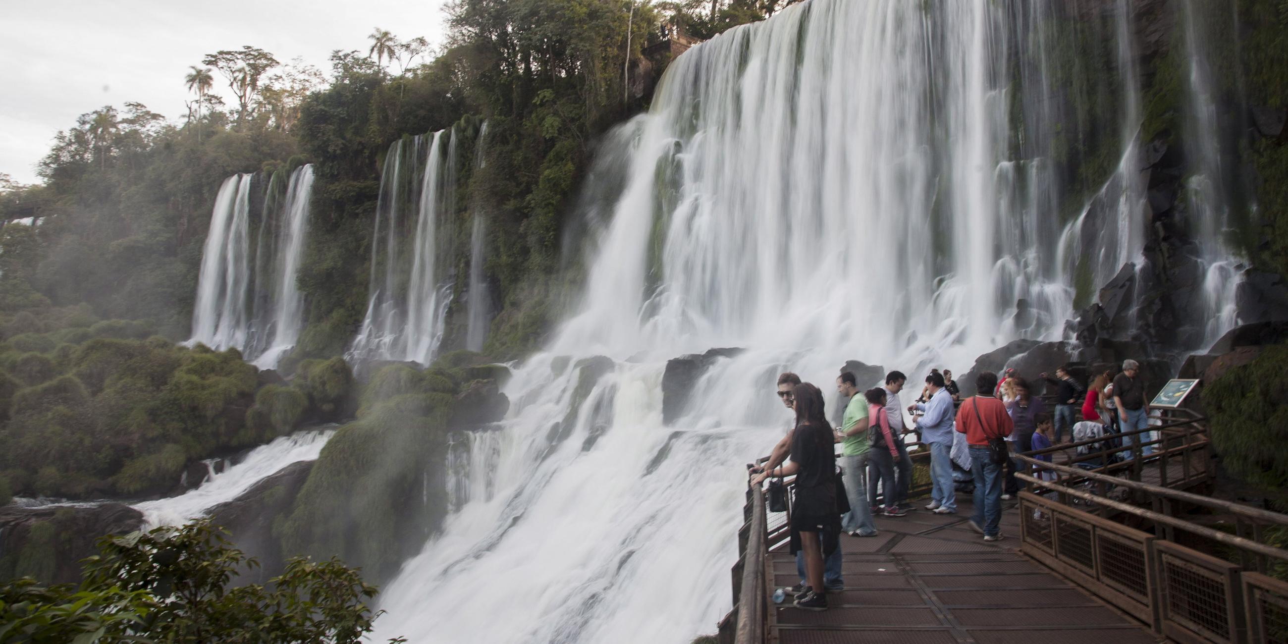 Menschen stehen auf der Aussichtsplattform an den Iguazu Wasserfällen