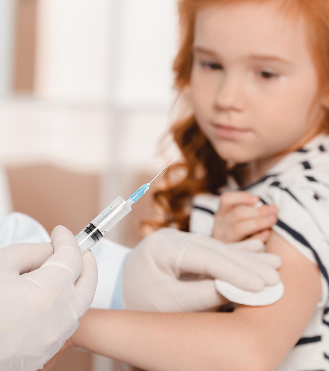 Arzt in medizinischen Handschuhen macht Injektion für kleines Mädchen in der Klinik.