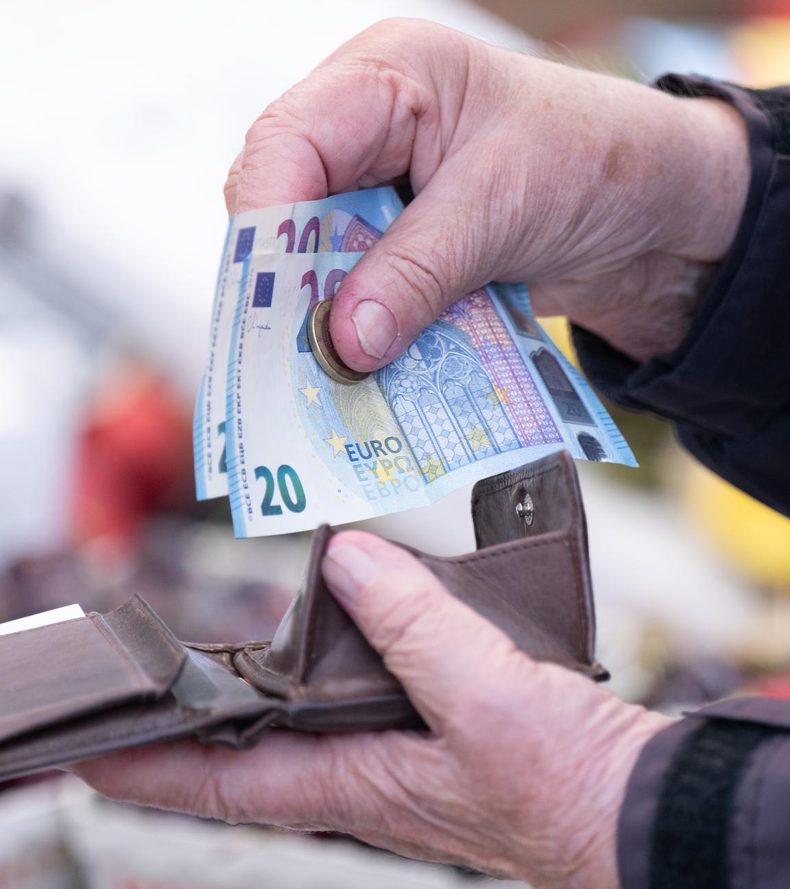 Sachsen, Dresden: Eine Frau sortiert auf einem Wochenmarkt das Wechselgeld für ihre Einkäufe in ein Portemonnaie.