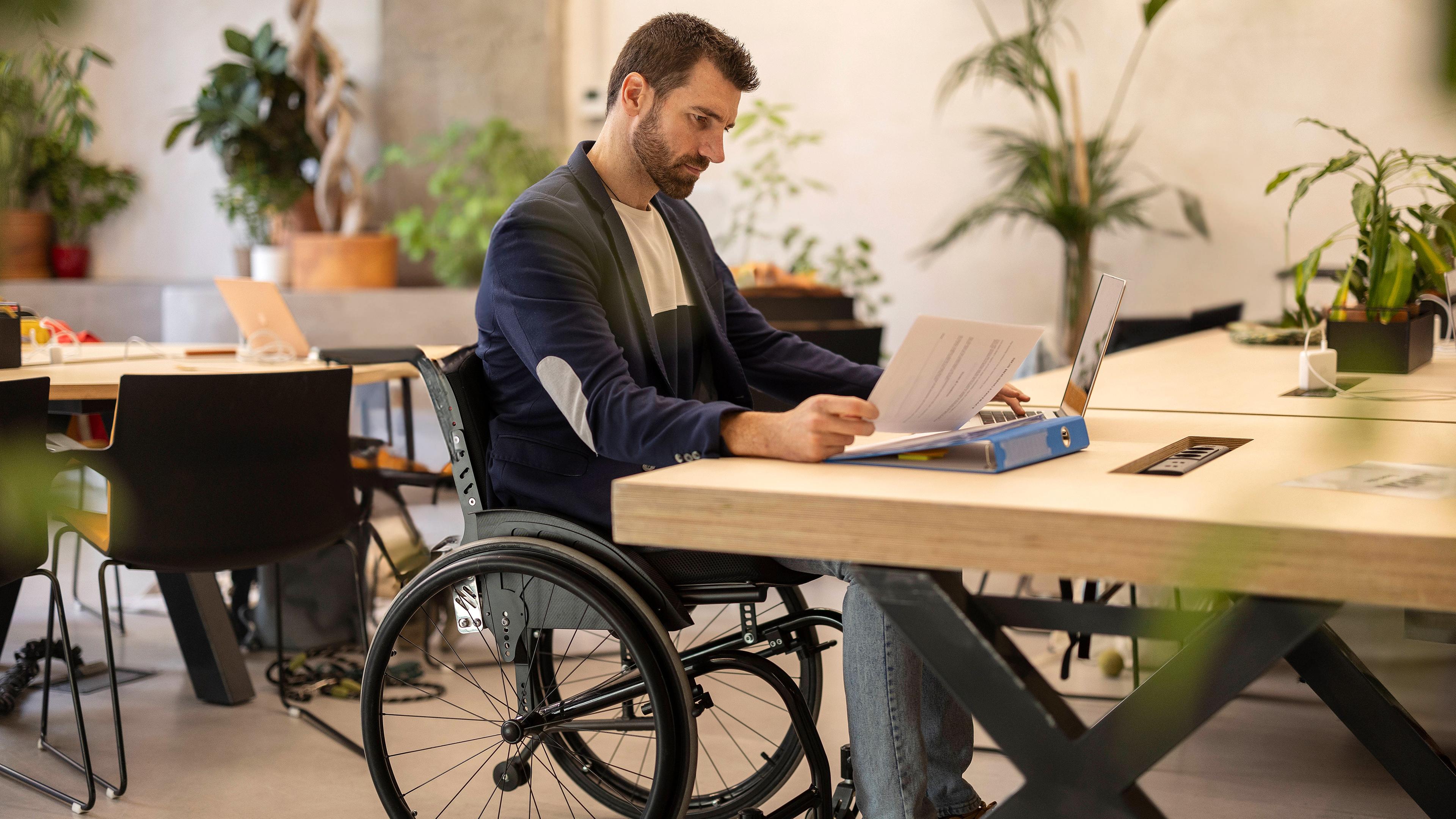 Ein Mann sitz im Rollstuhl am Arbeitsplatz