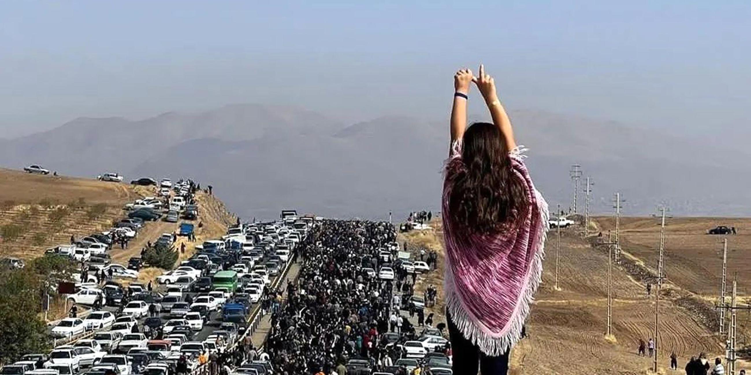 Eine Frau steht bei einem Protest im Iran auf einem Auto.