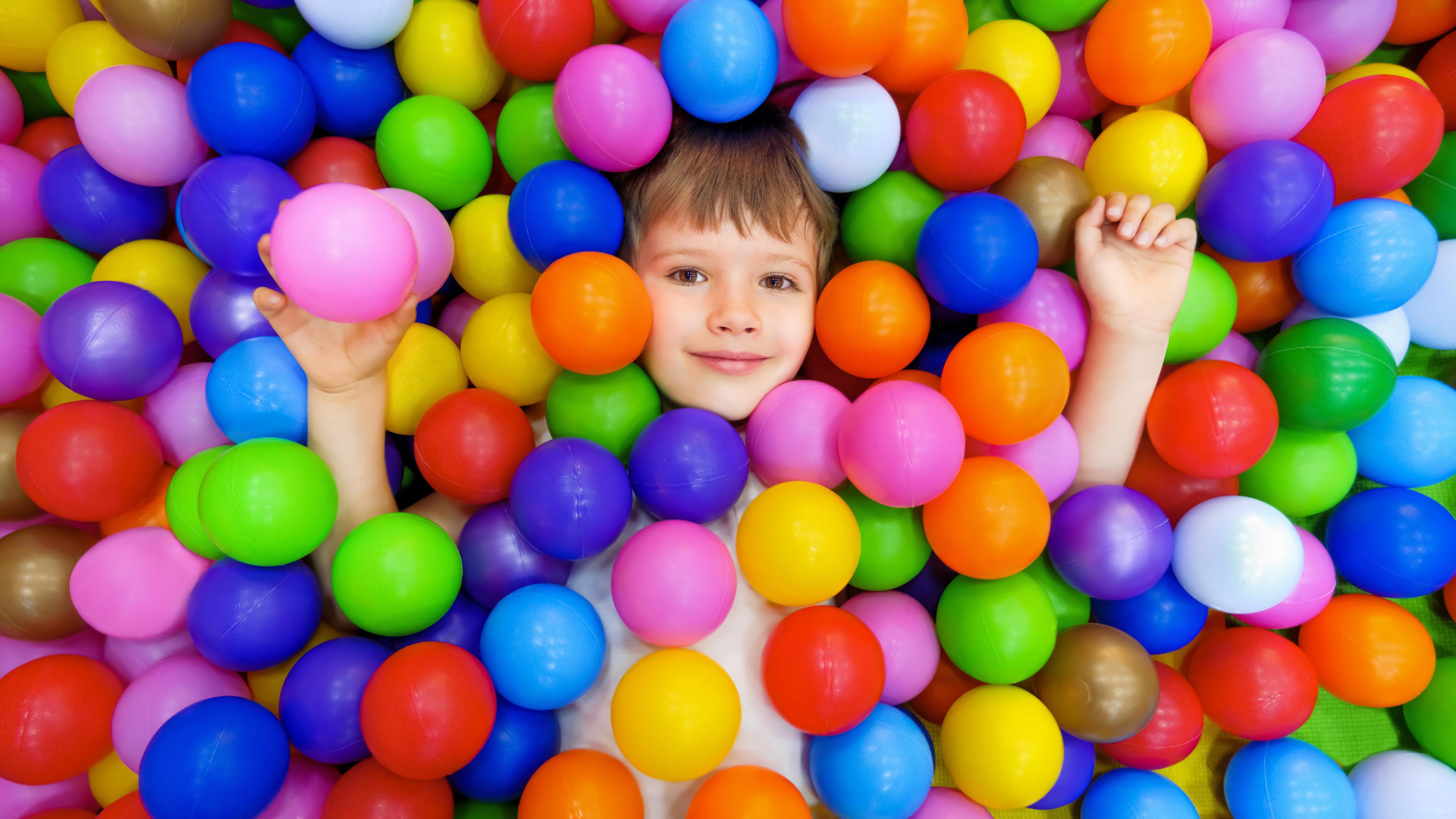 Smile kid lying colorful plastic balls pool. 