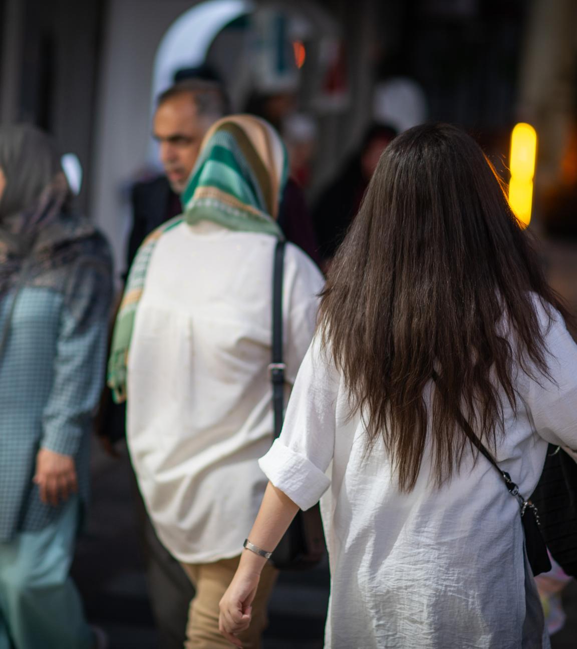 Eine Frau läuft in Teheran mit offenen Haaren am Abend eine Straße entlang.