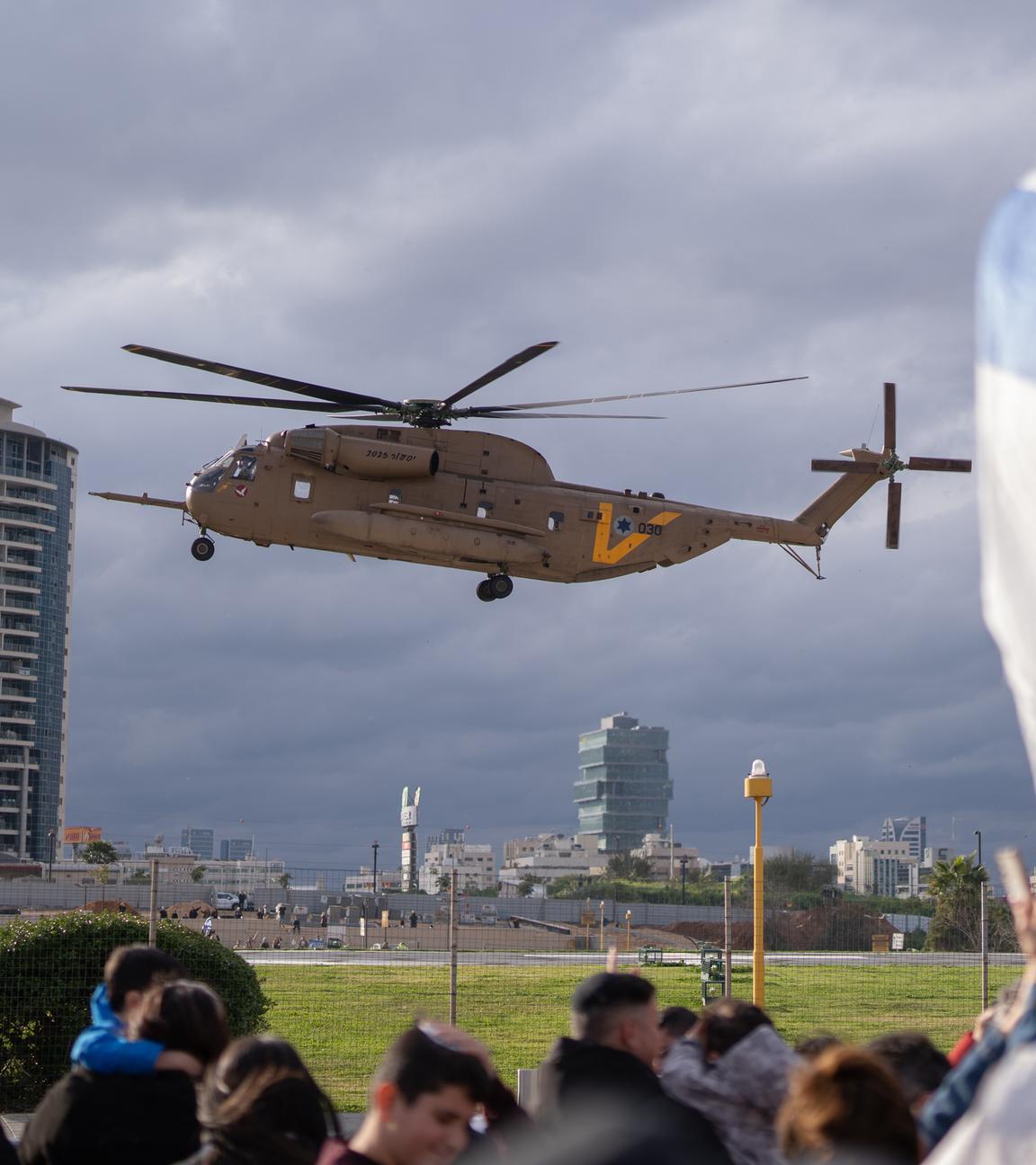 Eine Hubschrauber bei seiner Landung vor wartenden Menschen mit einer Israel-Flagge