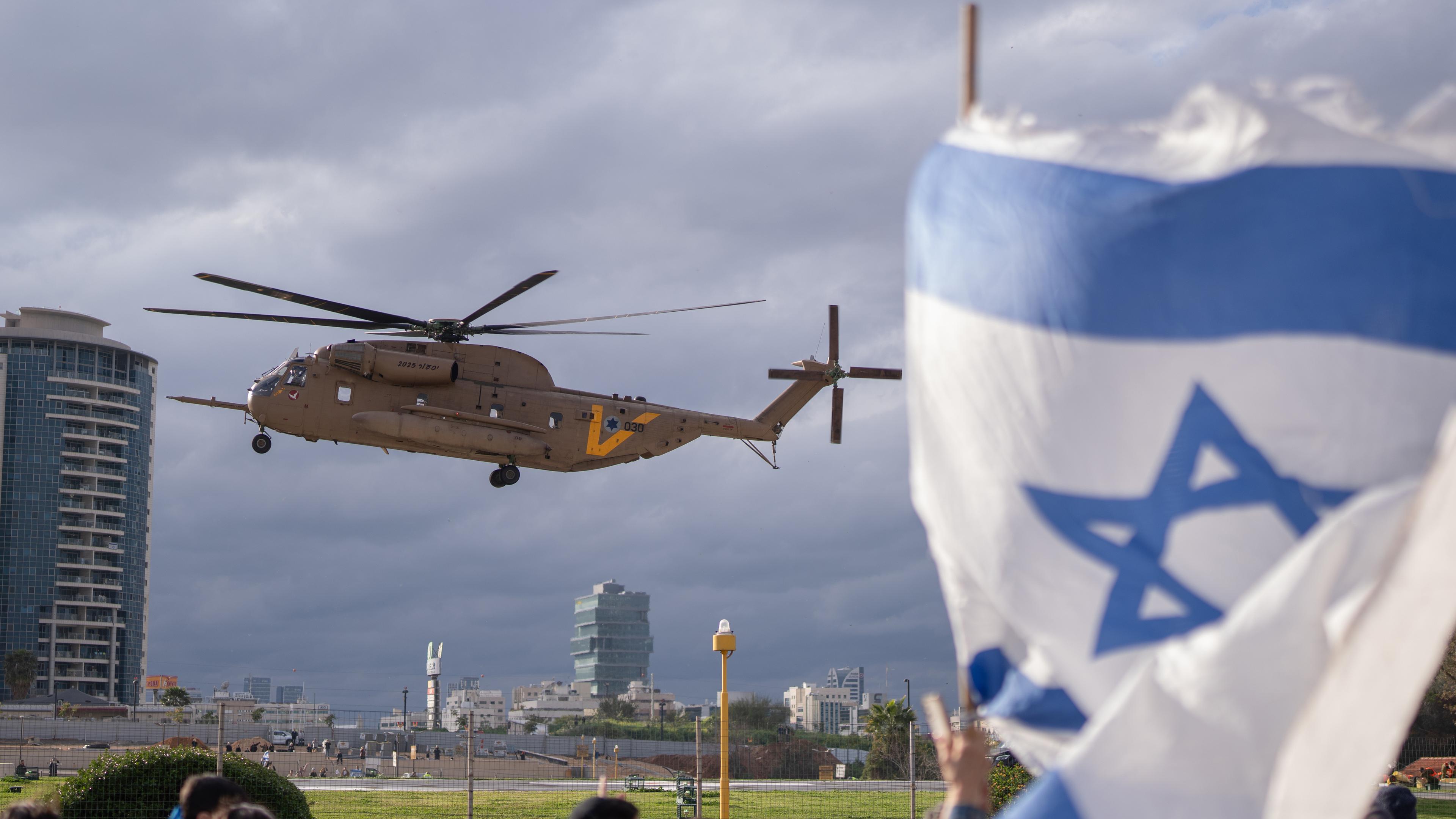 Eine Hubschrauber bei seiner Landung vor wartenden Menschen mit einer Israel-Flagge