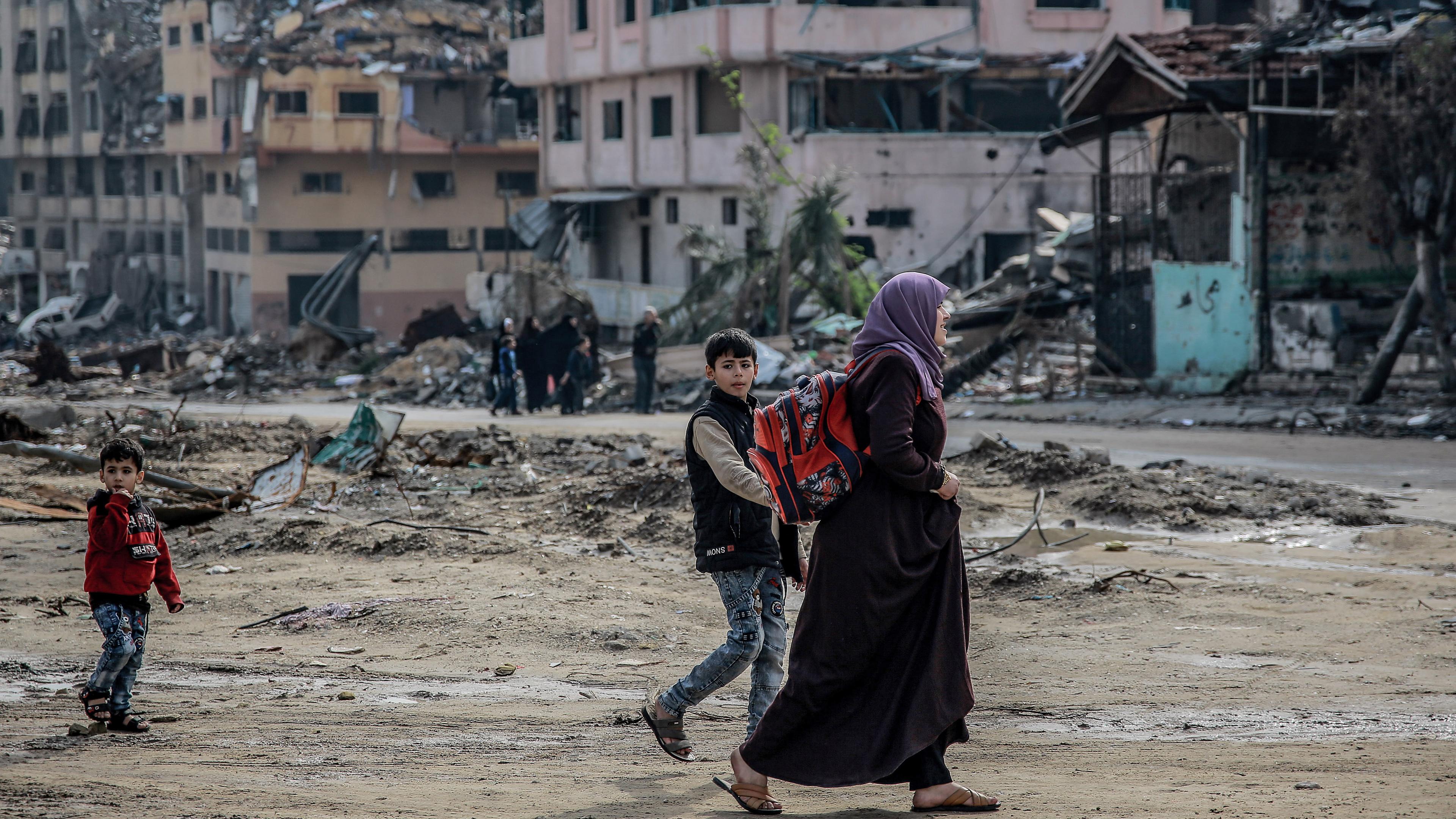 Eine palästinensische Frau geht mit ihren Kindern durch das zerstörte Viertel Sheikh Radwan in Gaza-Stadt, aufgenommen am 15.01.2024