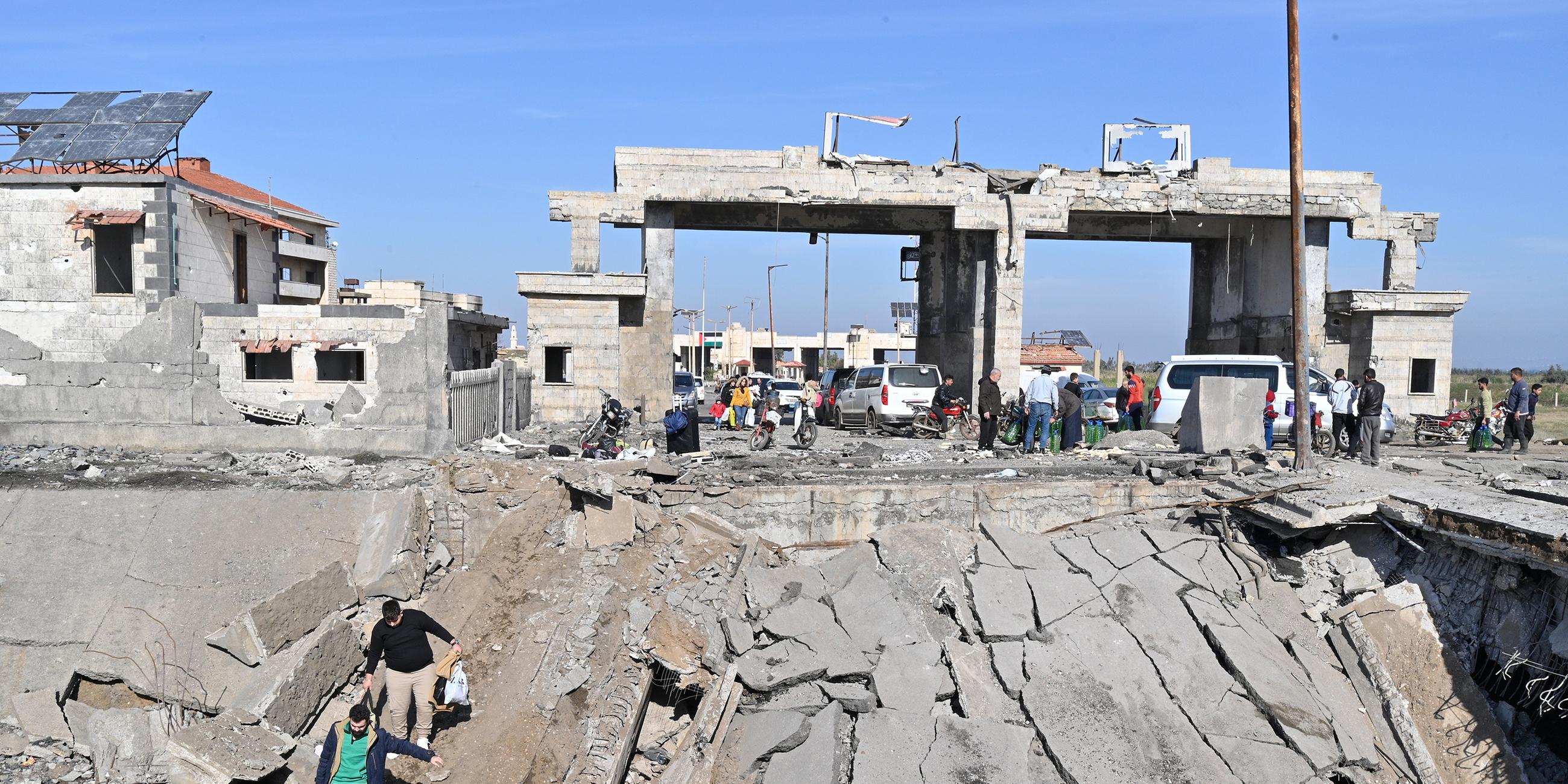 Menschen, darunter syrische und libanesische Vertriebene, überqueren den zerstörten Grenzübergang Arida zwischen den beiden Ländern in Akkar