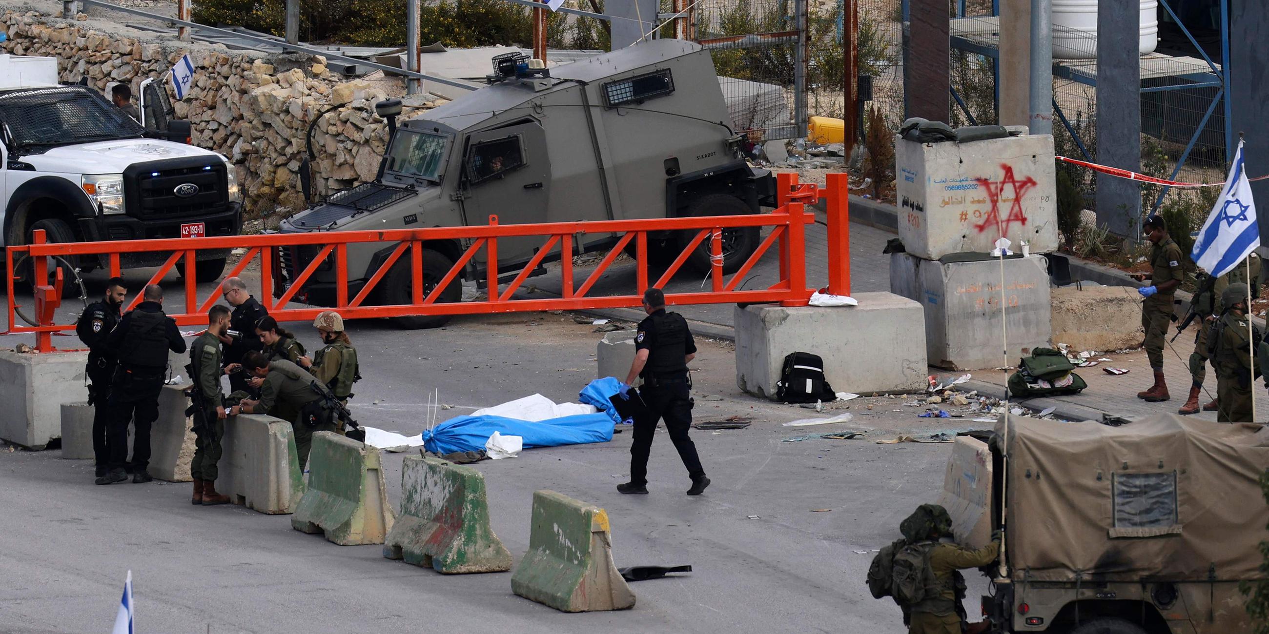 Israelische Sicherheitskräfte stehen neben den Leichen zweier palästinensischer Männer an einem Kontrollpunkt nahe Hebron