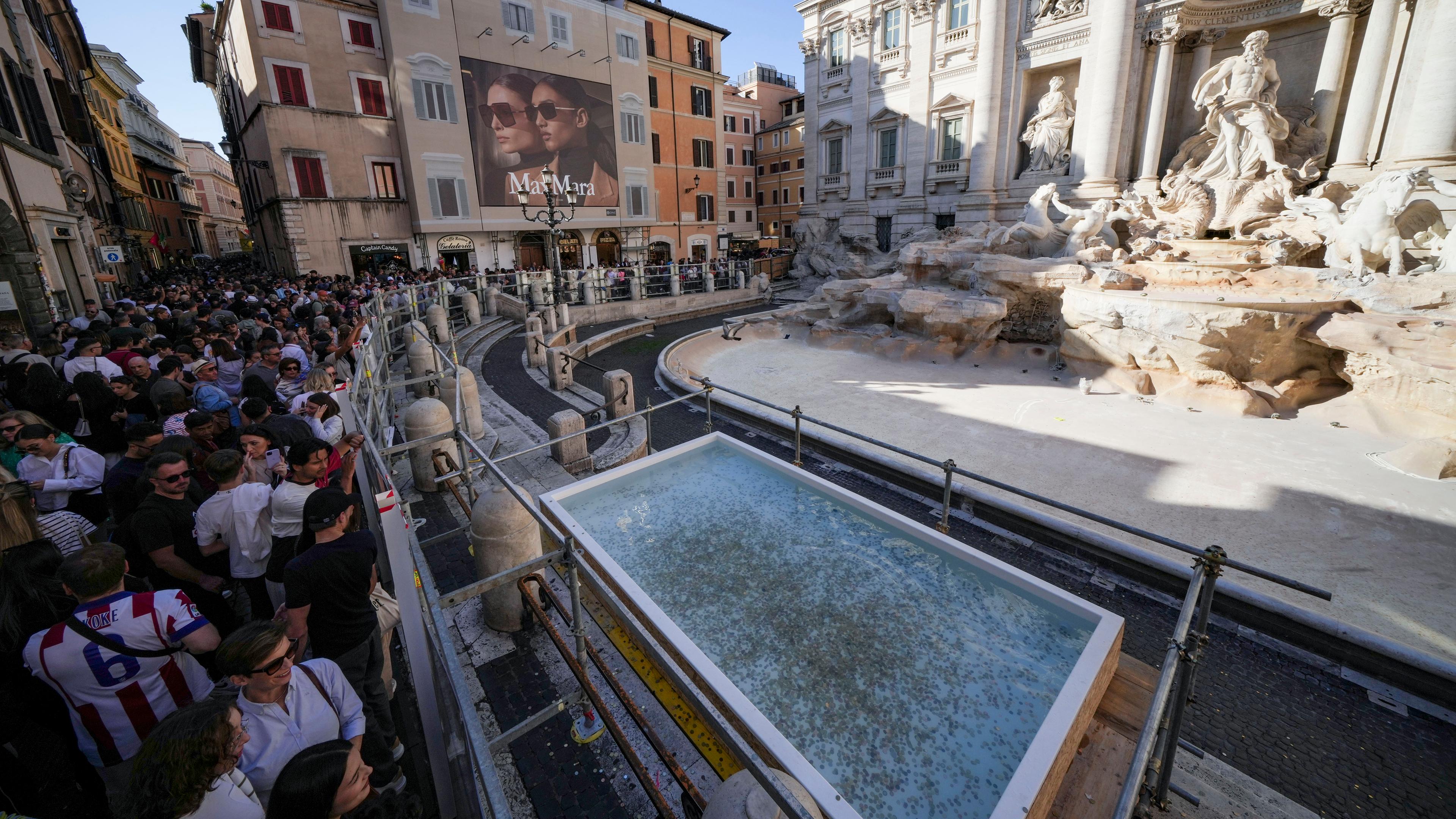 Italian, Rom: Vor dem Trevi-Brunnen ist ein kleiner Teich zu sehen, in den Touristen ihre Münzen werfen können, da der Brunnen geleert wurde, um Wartungsarbeiten durchzuführen