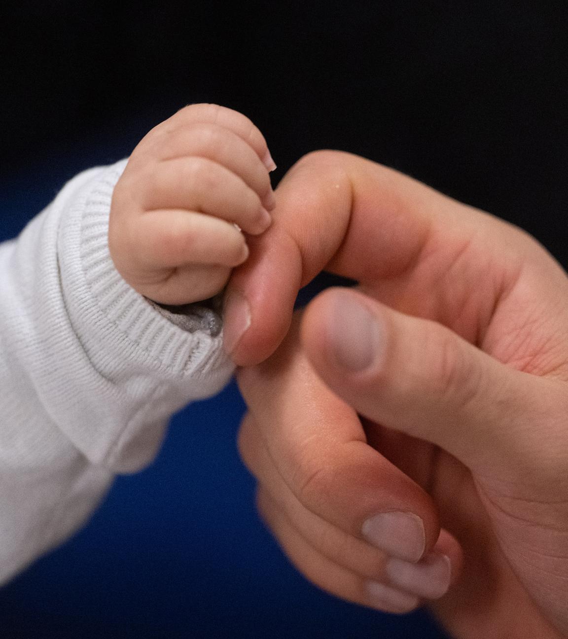 Ein Vater berührt die Hand seines Kindes.