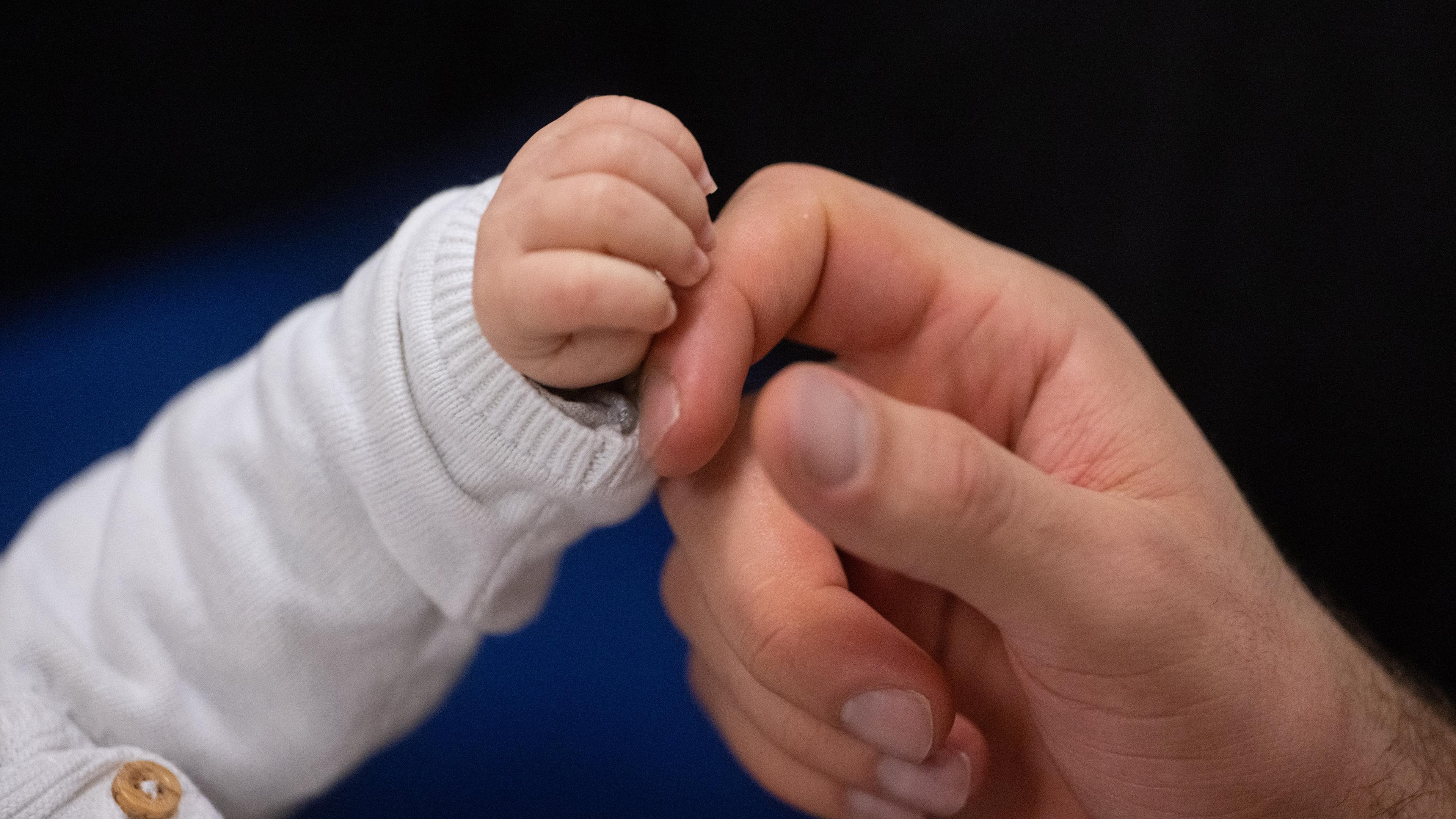 Ein Vater berührt die Hand seines Kindes.