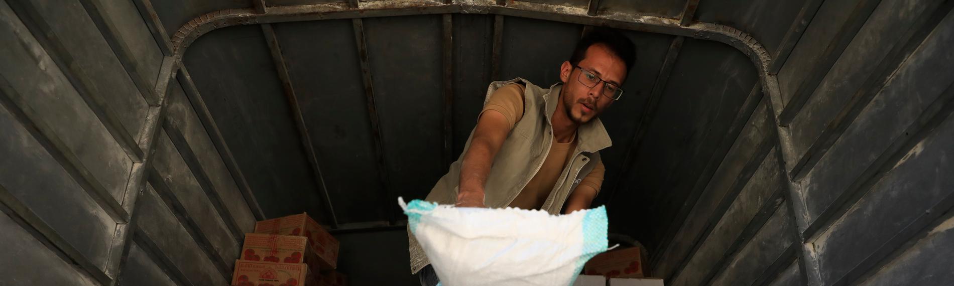 An aid worker unloads food aid from a truck provided by a local relief agency for vulnerable families amid food insecurity, in Sana'a, Yemen, 30 January 2024.