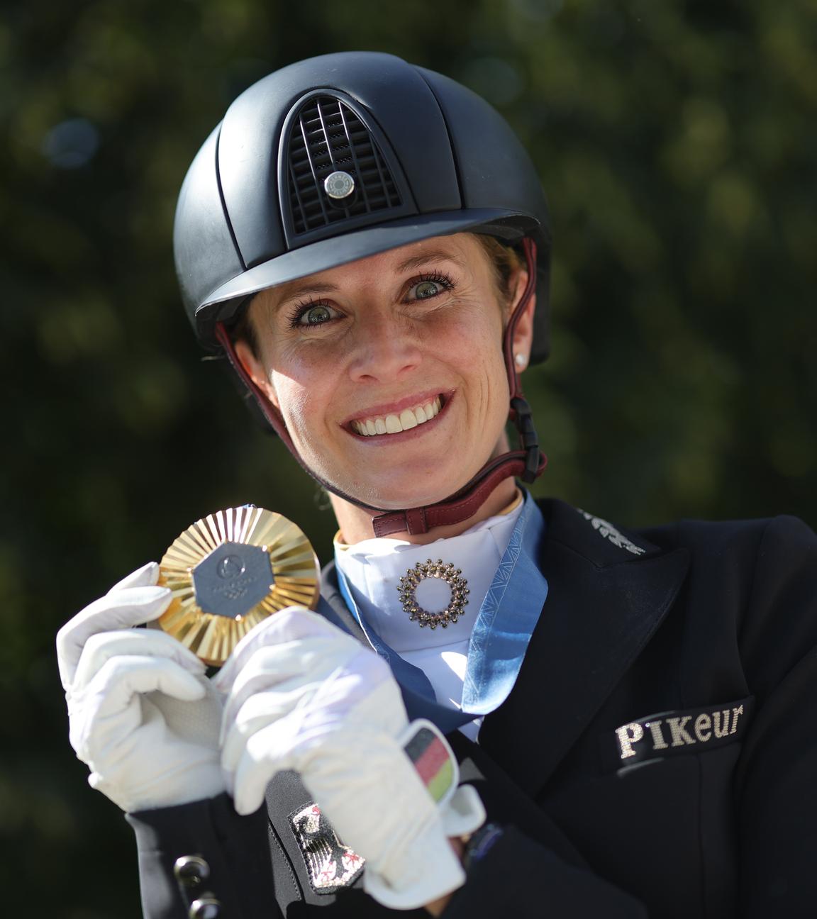 Deutschlands Jessica von Bredow-Werndl zeigt nach der Siegerehrung ihre Goldmedaille.