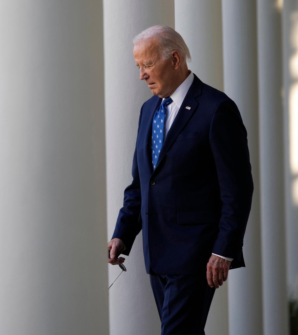 Präsident Joe Biden verlässt im Anzug den Rosengarten des Weißen Hauses in Washington, um eine Rede zu halten. Er schaut nach unten.