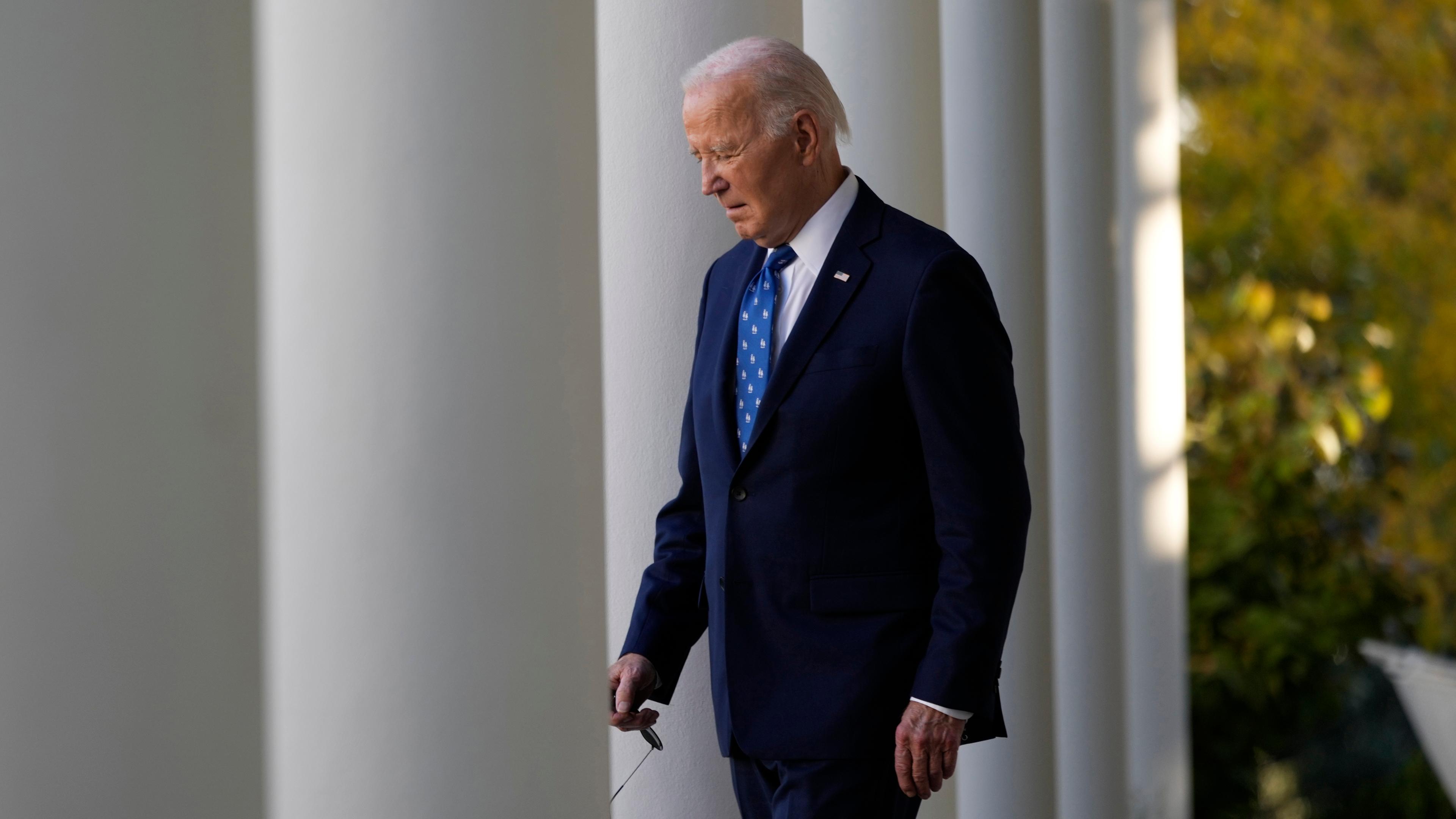 Präsident Joe Biden verlässt im Anzug den Rosengarten des Weißen Hauses in Washington, um eine Rede zu halten. Er schaut nach unten.