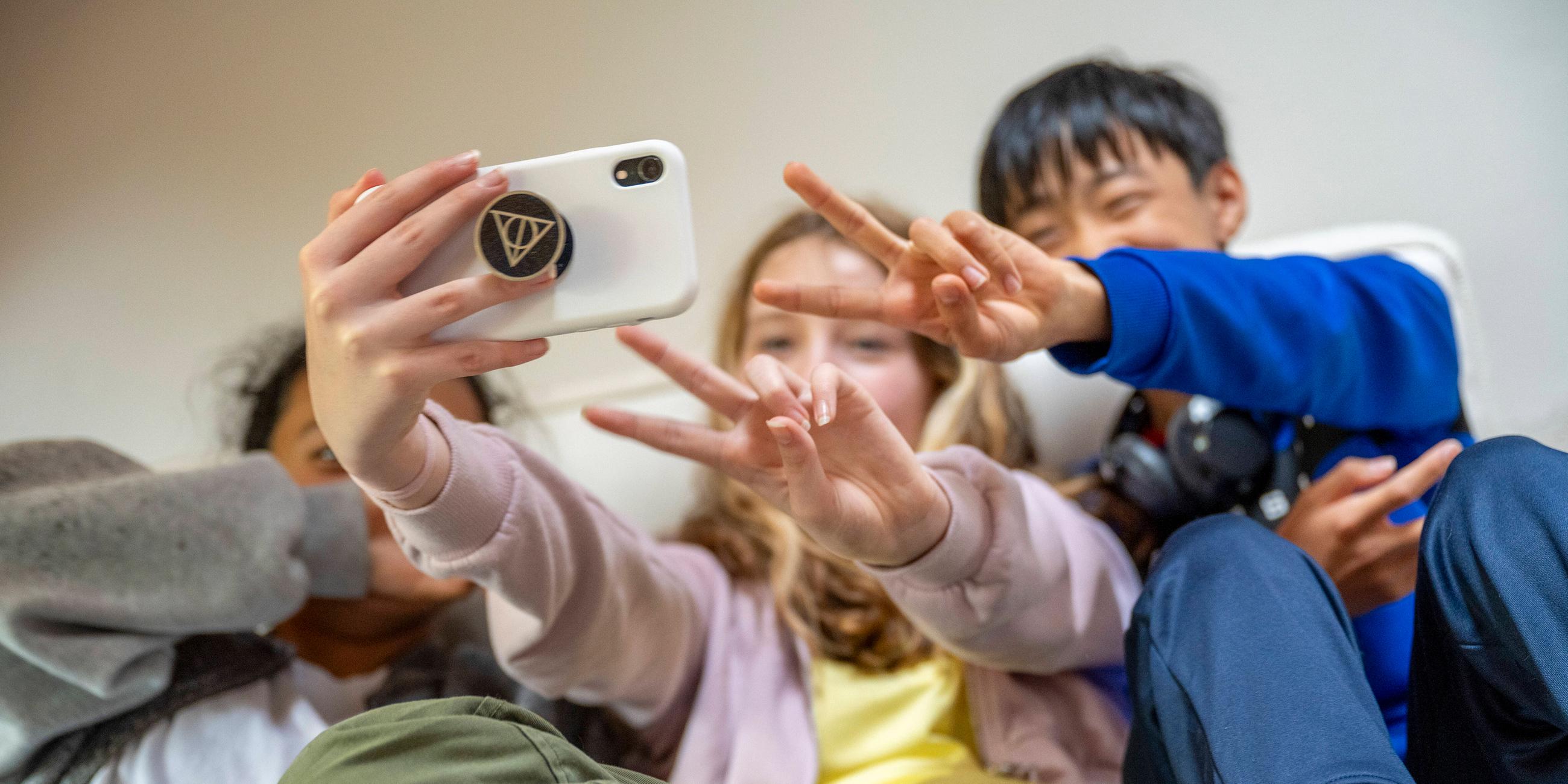 Drei Kinder machen ein Selfie mit einem Smartphone