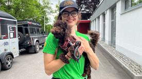 Julia Spielvogel carries a brown dog on her arm.