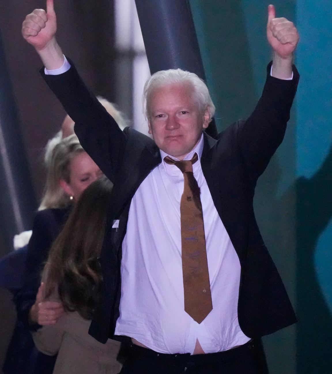 Julian Assange streckt seine Arme noch oben und zeigt zwei Daumen nach oben.