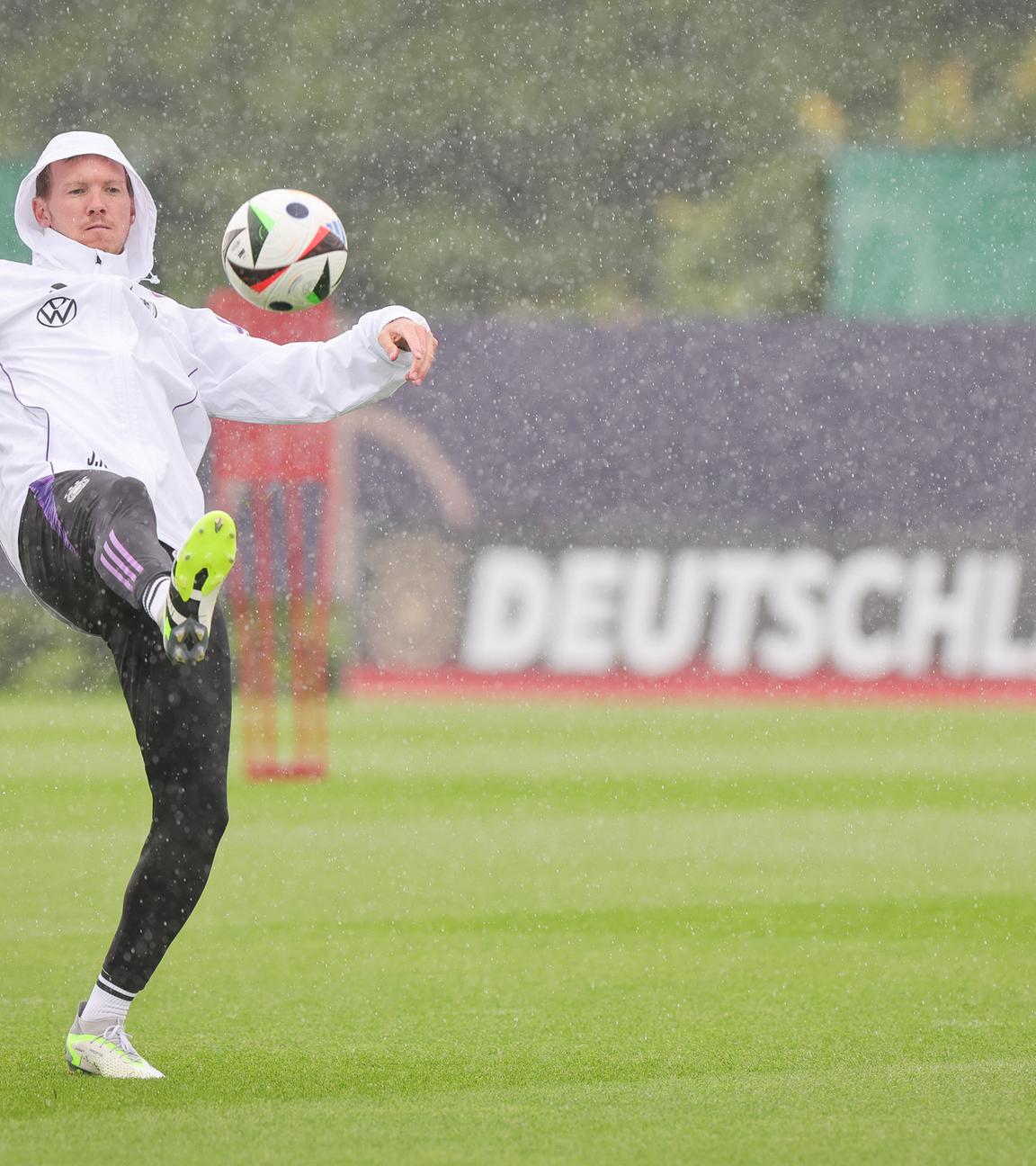 Deutschlands Trainer Julian Nagelsmann spielt einen Ball zu Beginn des Trainings im strömenden Regen. 