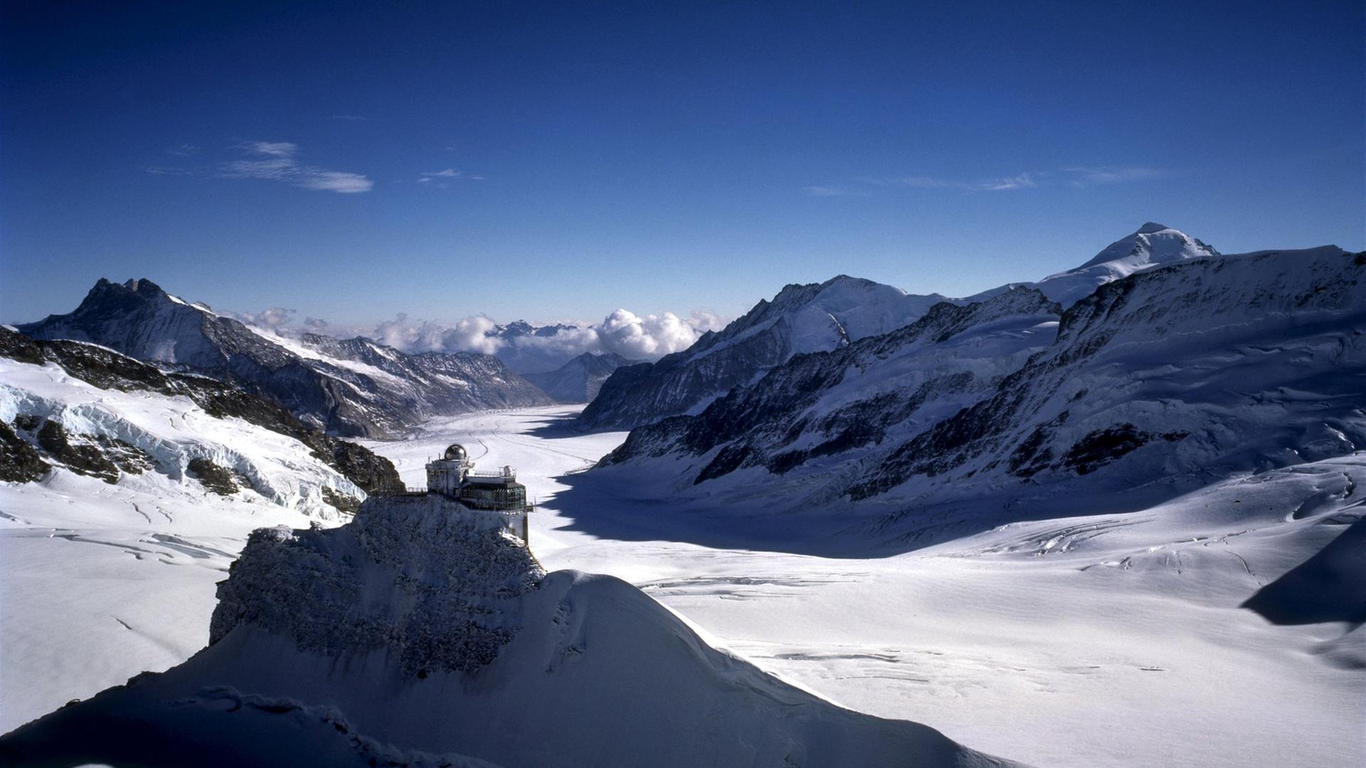 Panorama-Aufnahme: Schneebedeckte Berge unter blauem Himmel