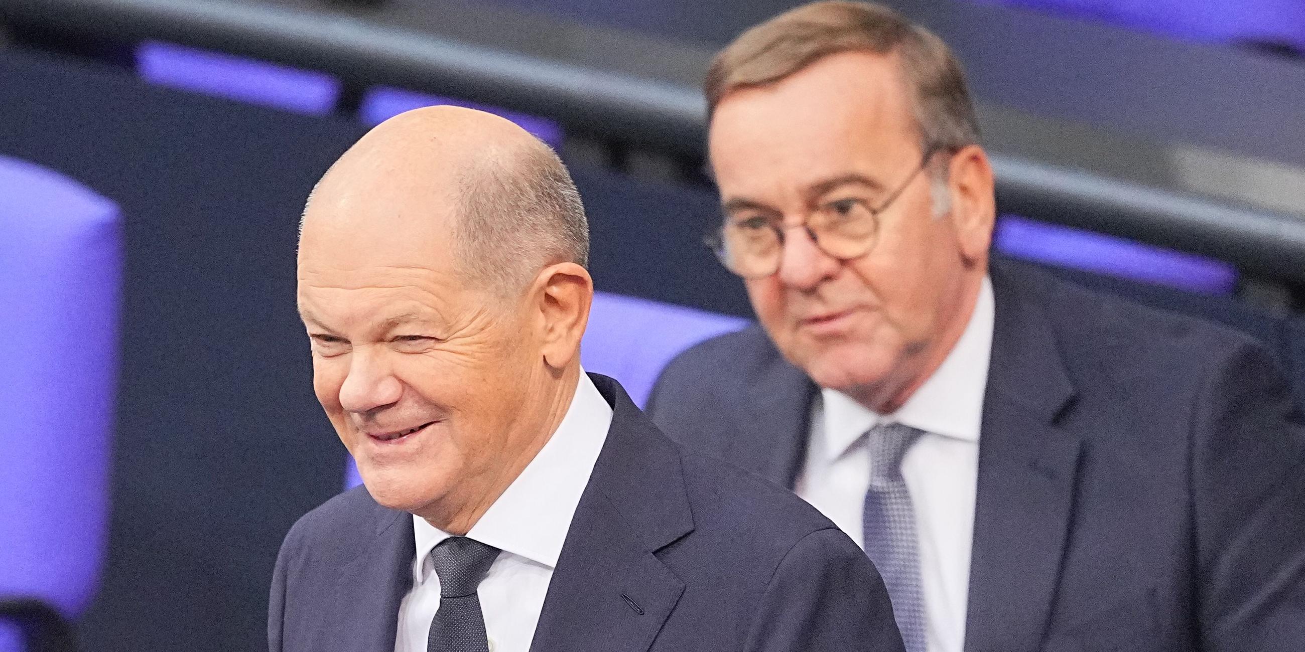 Bundeskanzler Olaf Scholz (SPD) steht lächelnd vor seiner Regierungserklärung im Plenum des Bundestags vor Boris Pistorius (SPD), Bundesminister der Verteidigung.