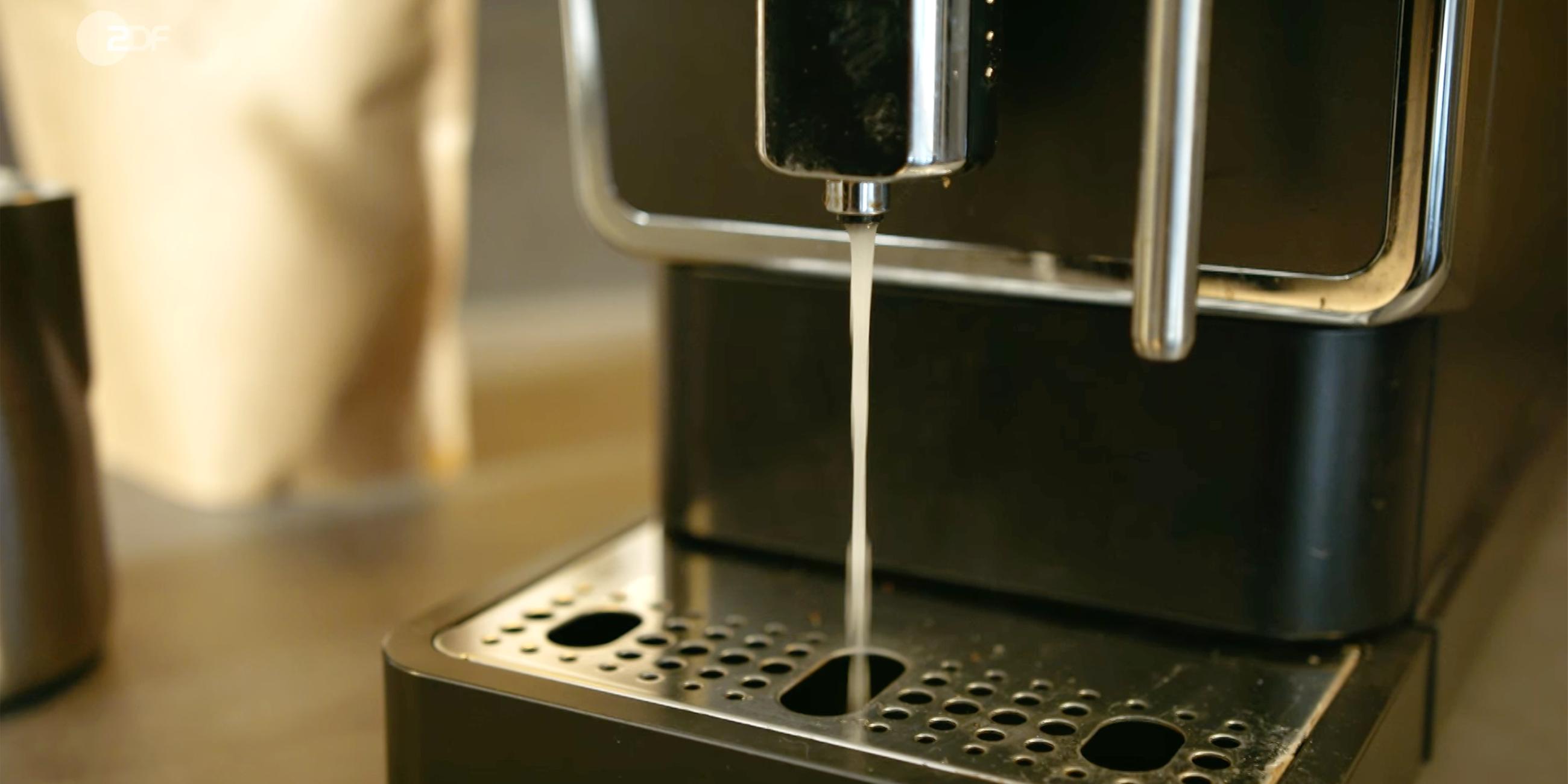Aus einer Kaffeemaschine läudft trübes Wasser, sie reinigt sich.