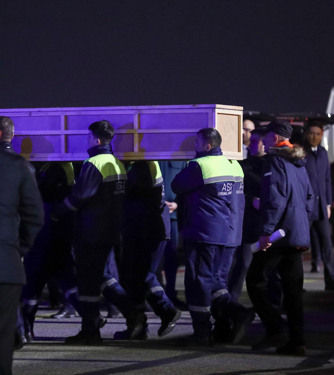 Arbeiter tragen auf dem internationalen Flughafen Heydar Aliyev außerhalb von Baku, Aserbaidschan, einen Sarg mit der Leiche eines Opfers aus einem medizinisch ausgerüsteten Flugzeug